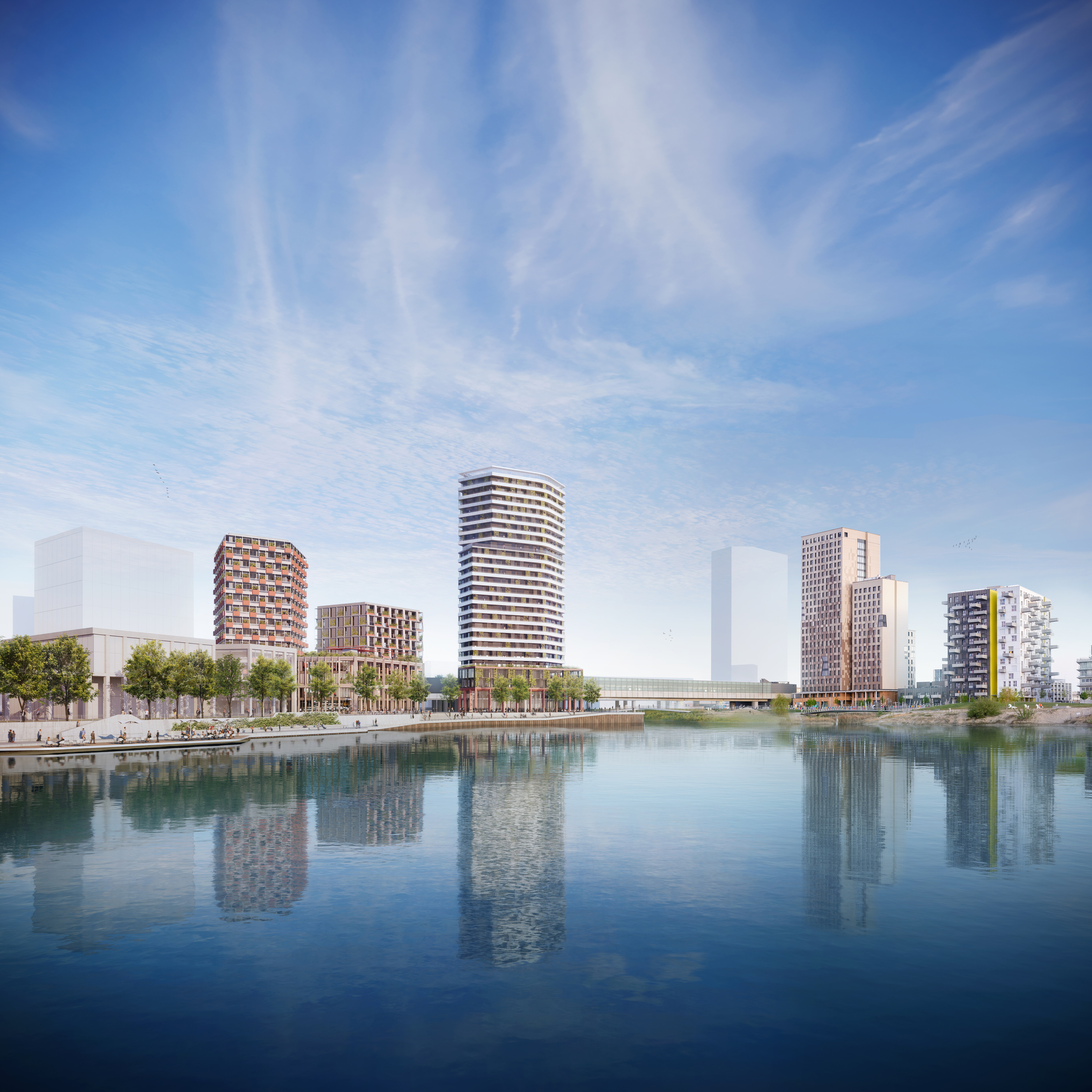 Der See im Vordergrund im Hintergrund vier Gebäude, zwei Hochhäuser, zwei niedrige, davor viele Bäume