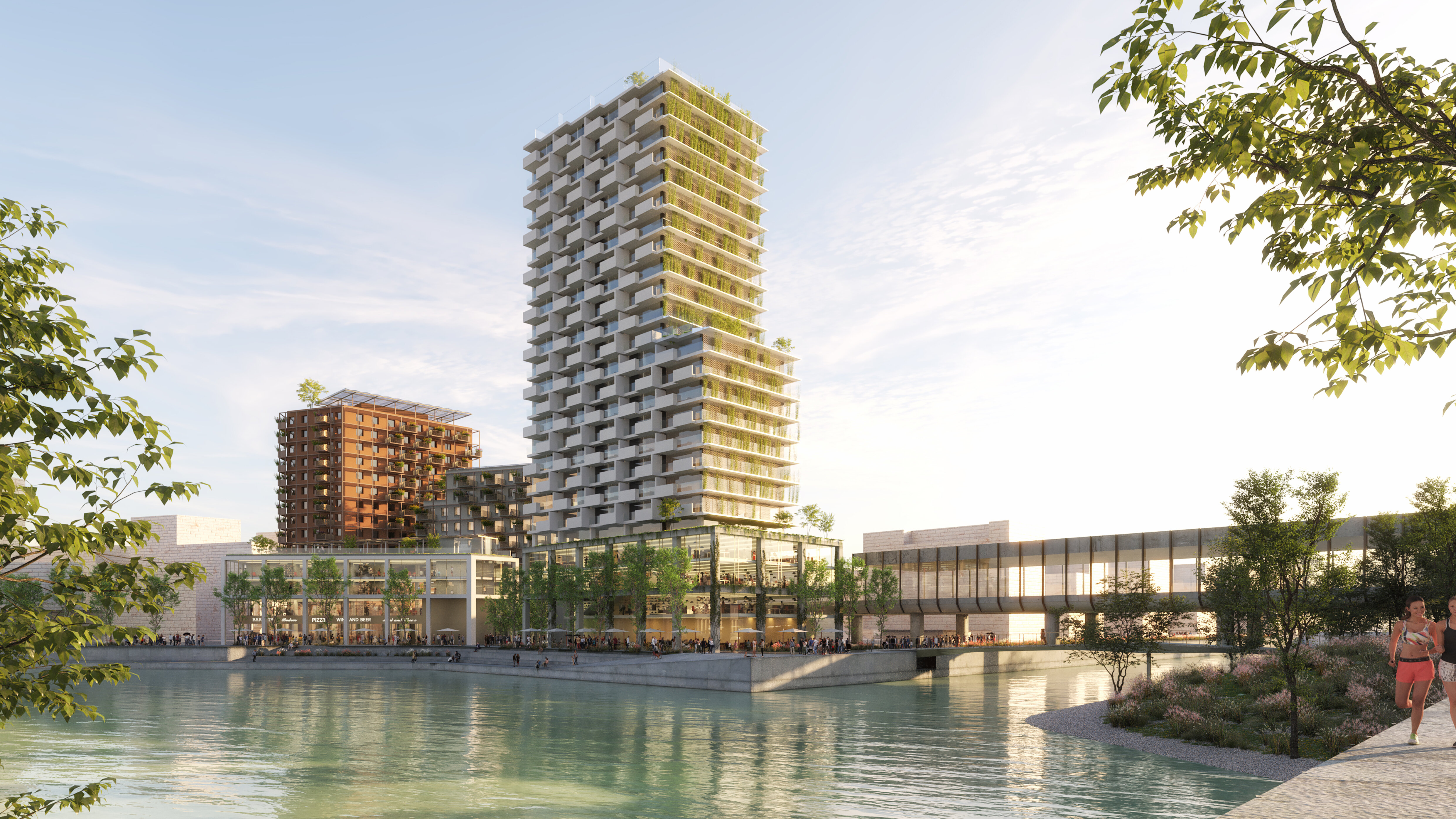 Im vorderen Teil der See, dahinter ein hohes sowie drei niedrigere Gebäude, die Promenade ohne Personen und rechts vom Bild eine U-Bahn-Station