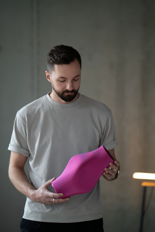 Mann hält eine pinke Vase in der Hand, Blick in Richtung Vase
