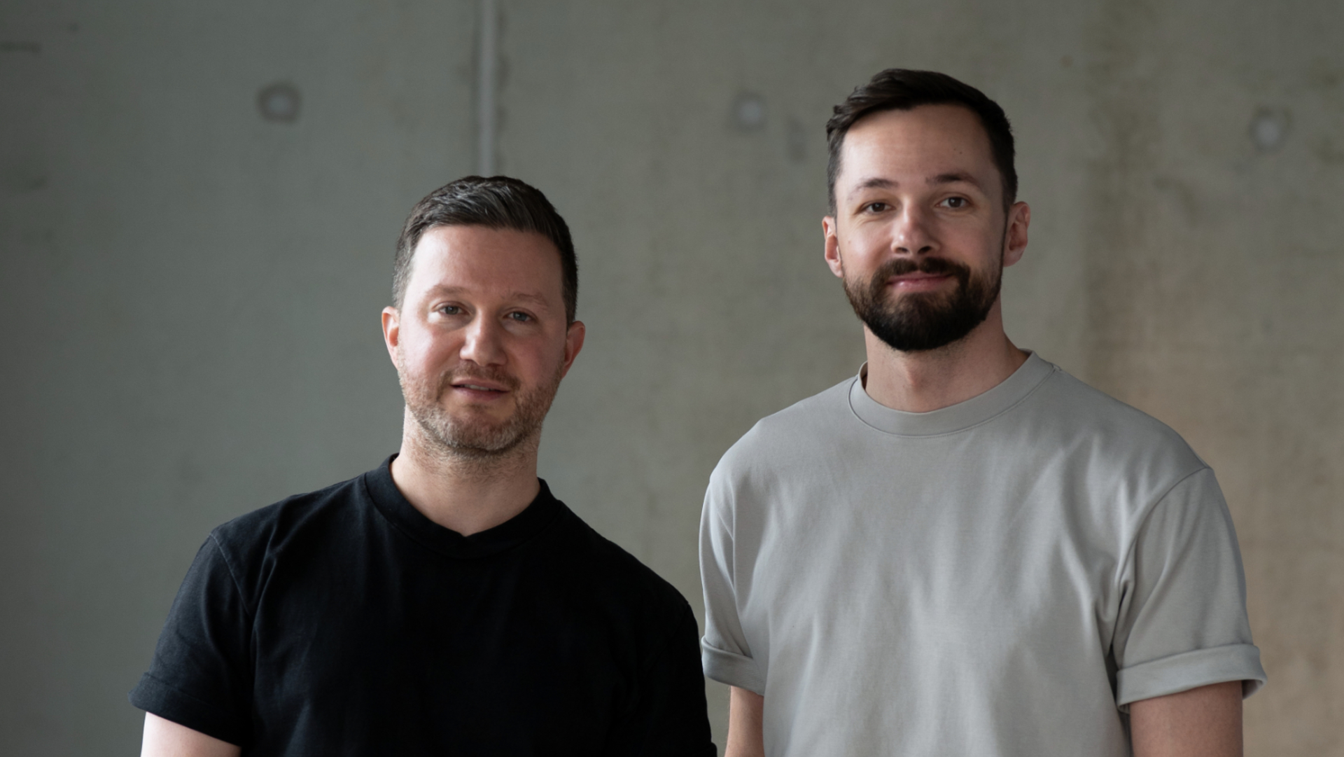 Zwei Männer schauen in die Kamera, es sind nur der Oberkörper und das Gesicht zu sehen