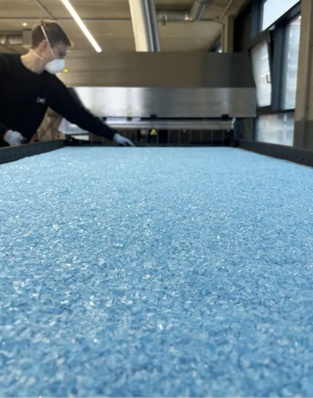 Blaue Paneele im Vordergrund, im Hintergrund ein Mann mit Munschutz und ein Gerät