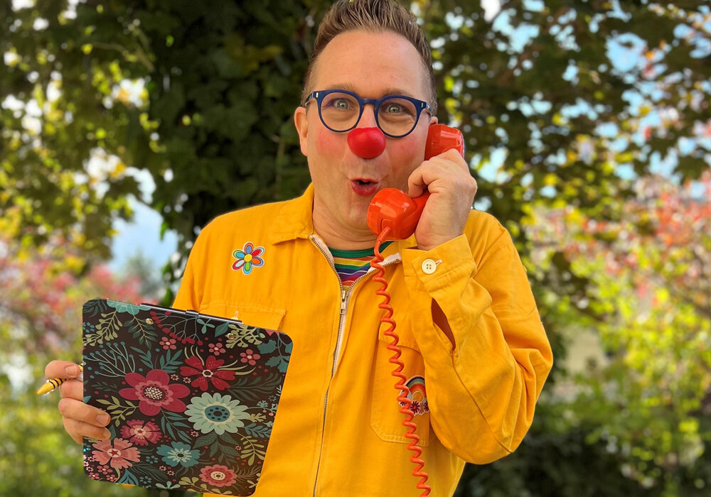 mensch als Clown verkleidet mit einem Telefon in der Hand
