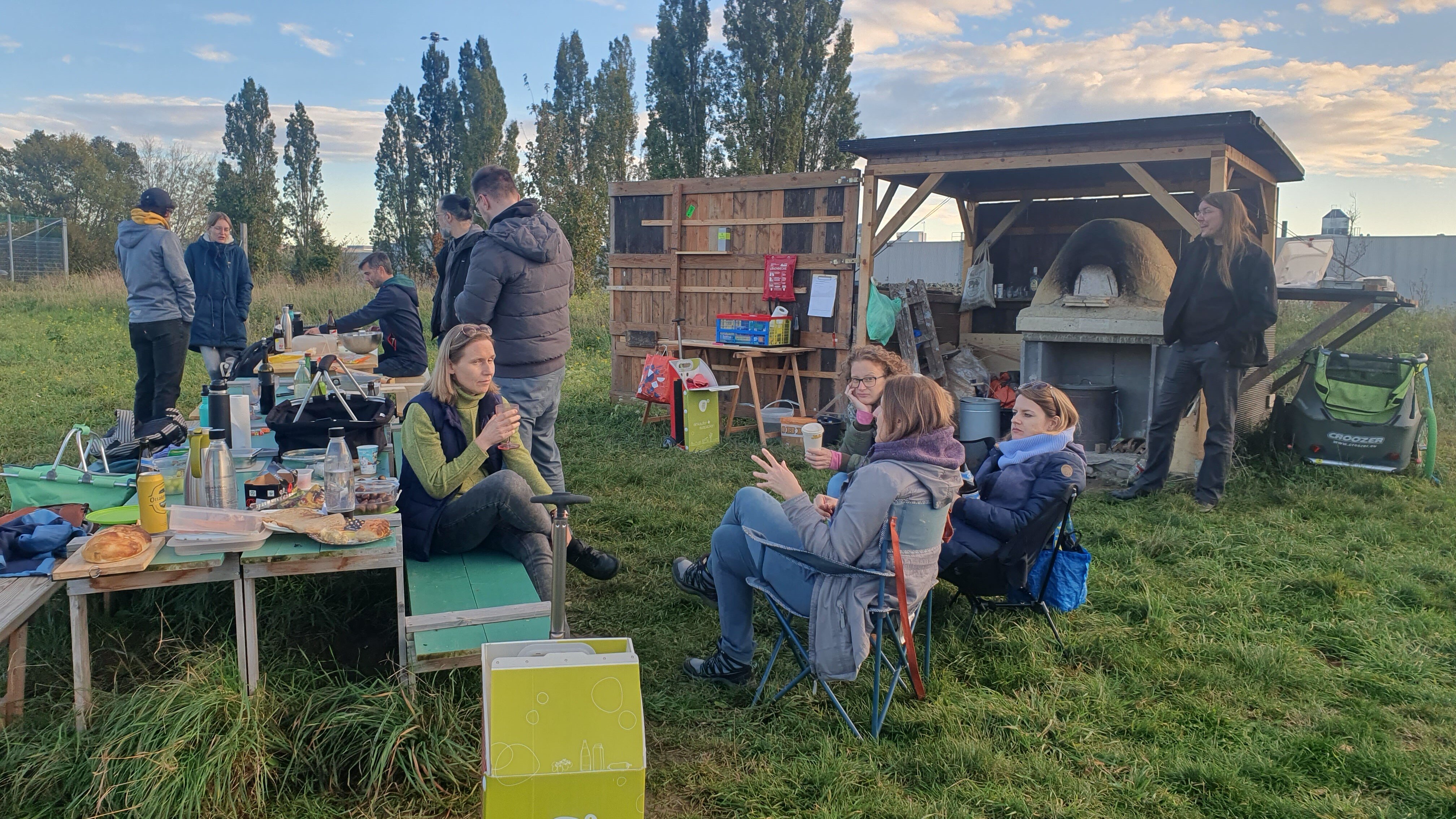 Menschen sthen um einem Pizzaofen auf der Wiese