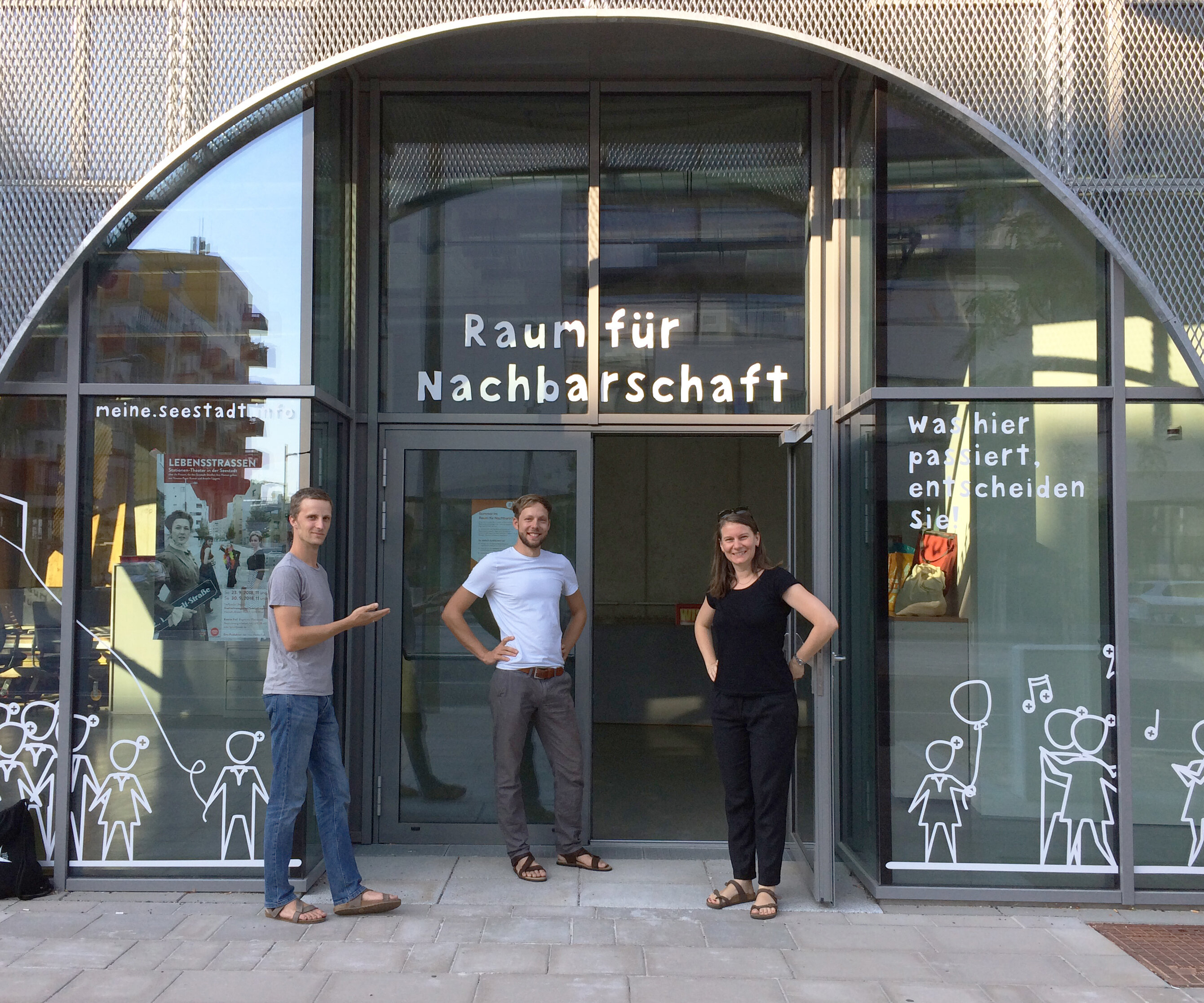 3 menschen stehen vor einer Glastüre