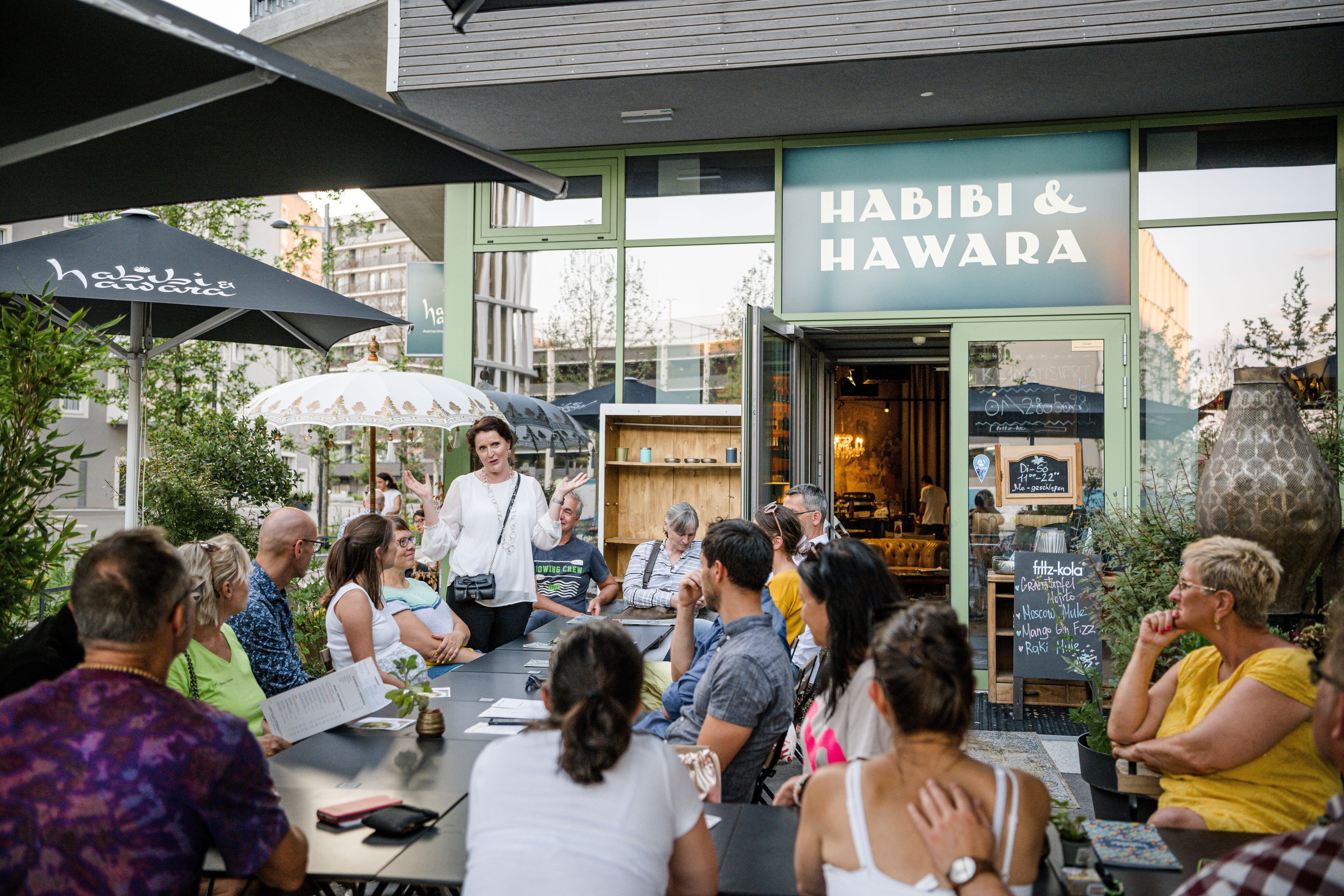 Menschen sitzen vor einem Lokal