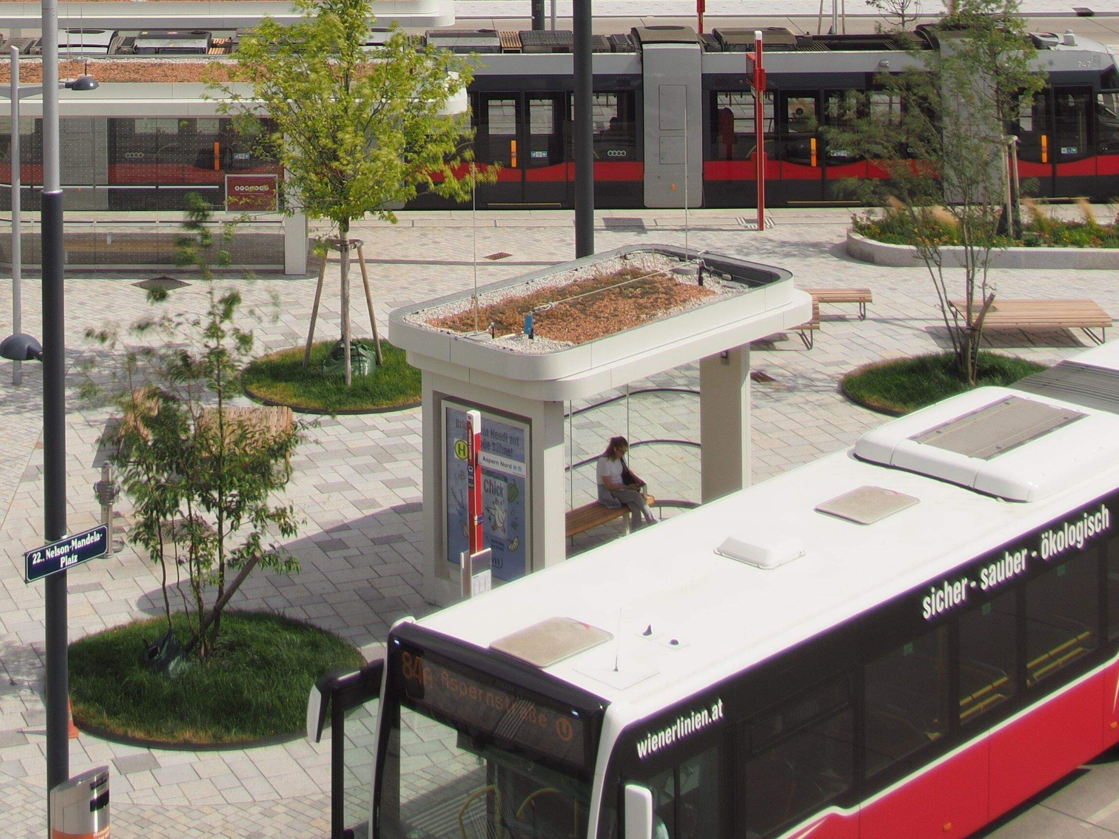 Foto des Platzes von schräg oben, Bus, Straßenbahn, Bäume und schöne Haltestationen und Pflasterung