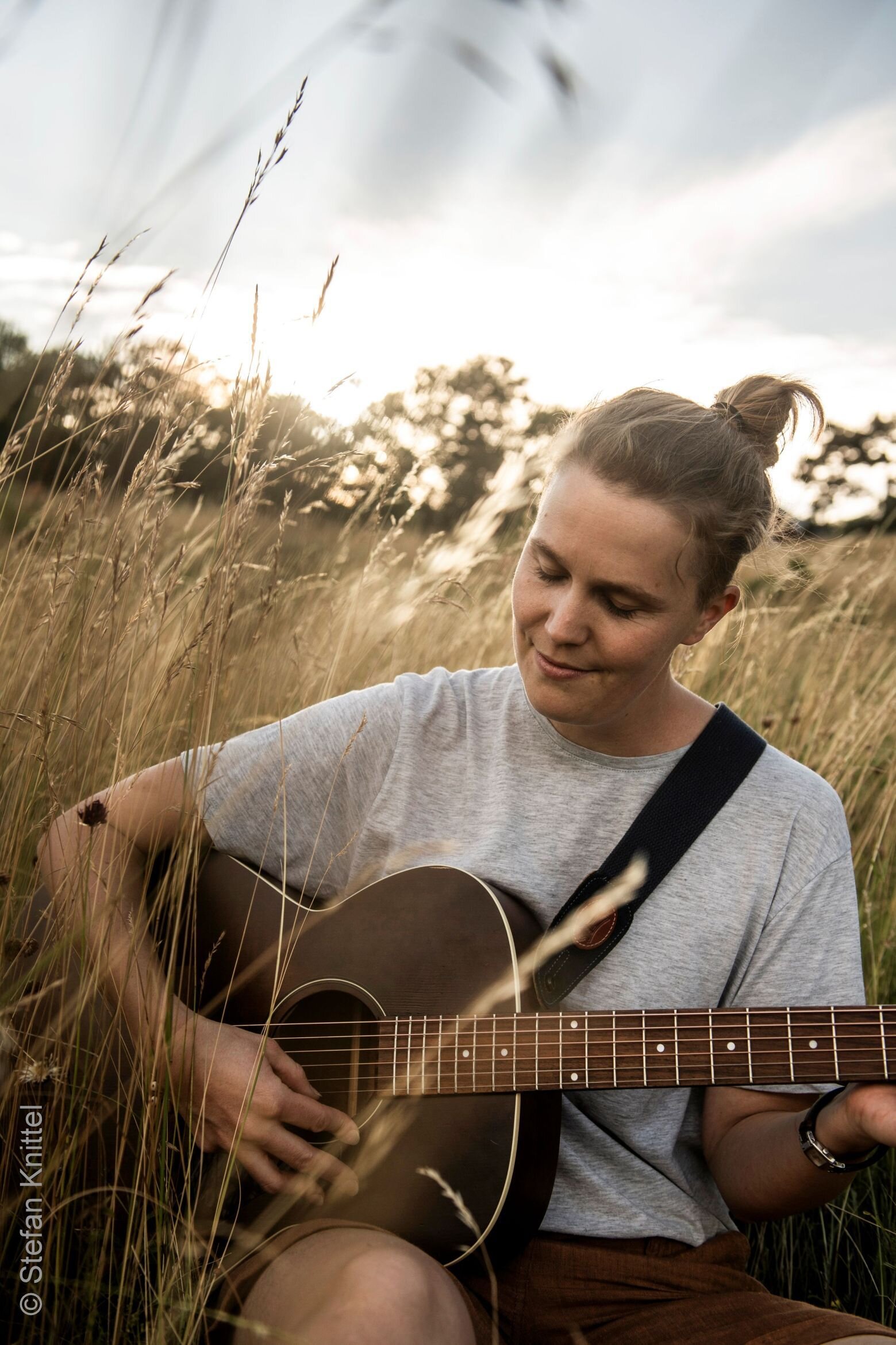 Frau mit Gitarre in einem Kornfeld
