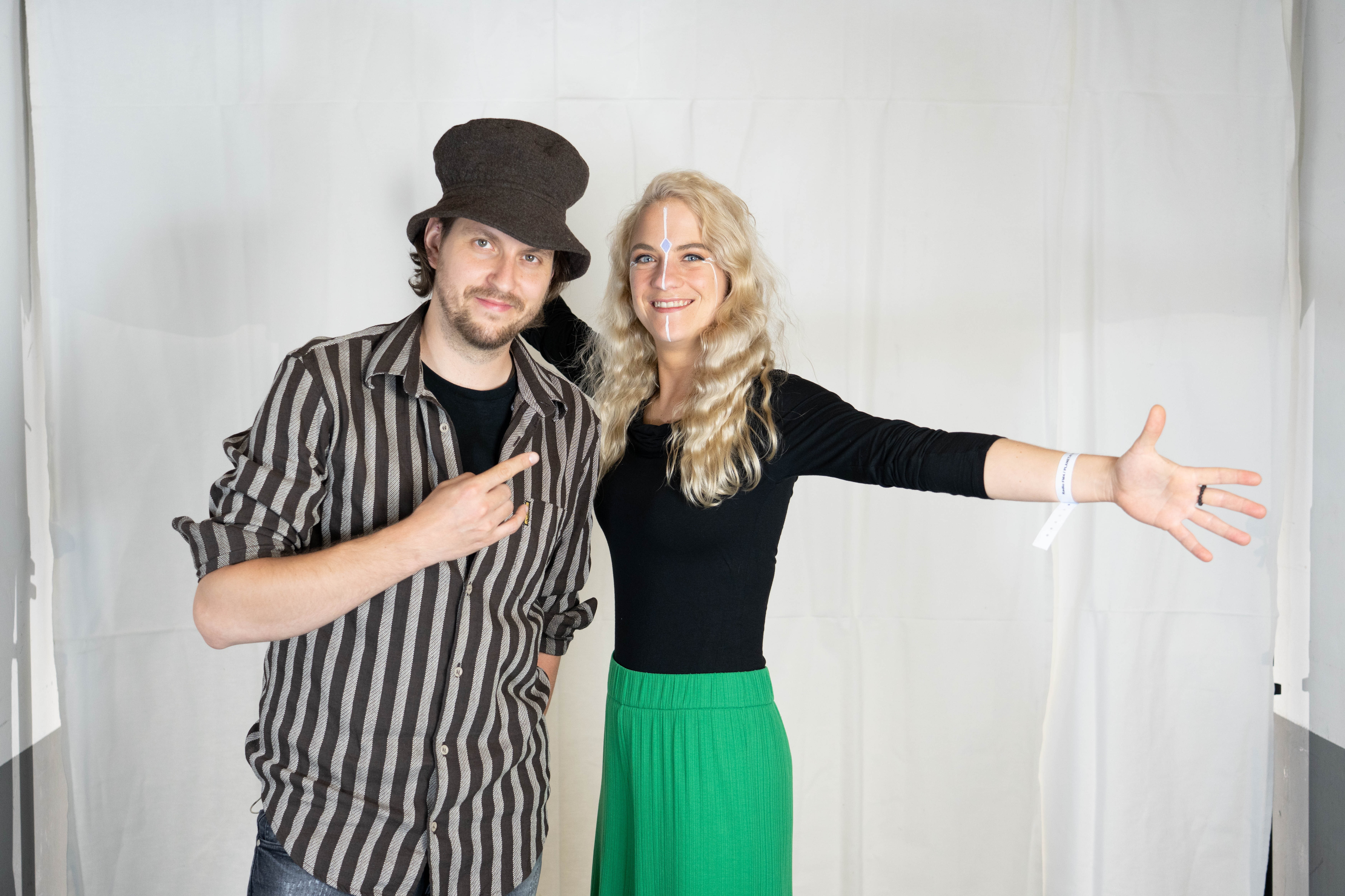 Ein Mann und eine Frau, er mit auffälligem Hut, sie mit grasgrünem Rock