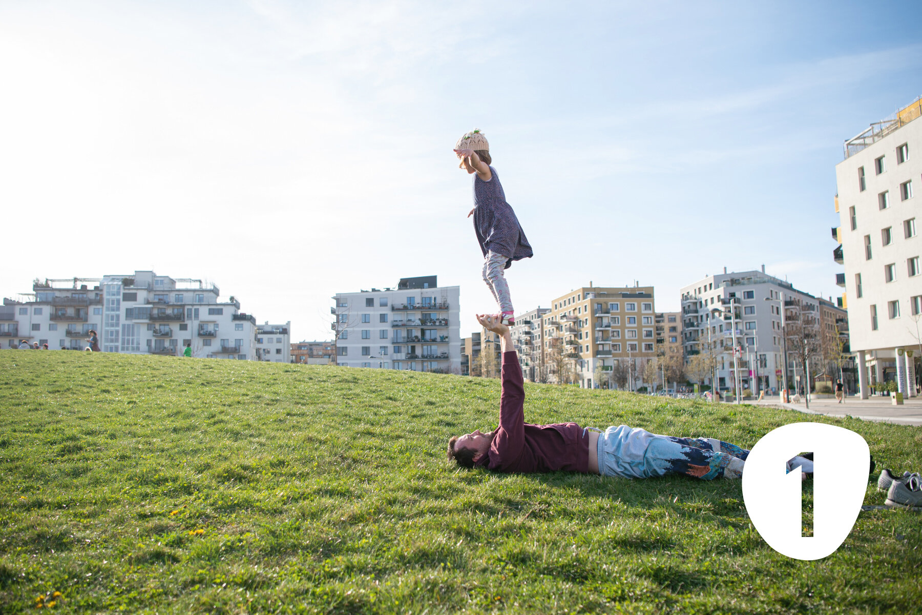 Ein Vater turnt mit Tochter auf einer Wiese im Park im Pionierquartier