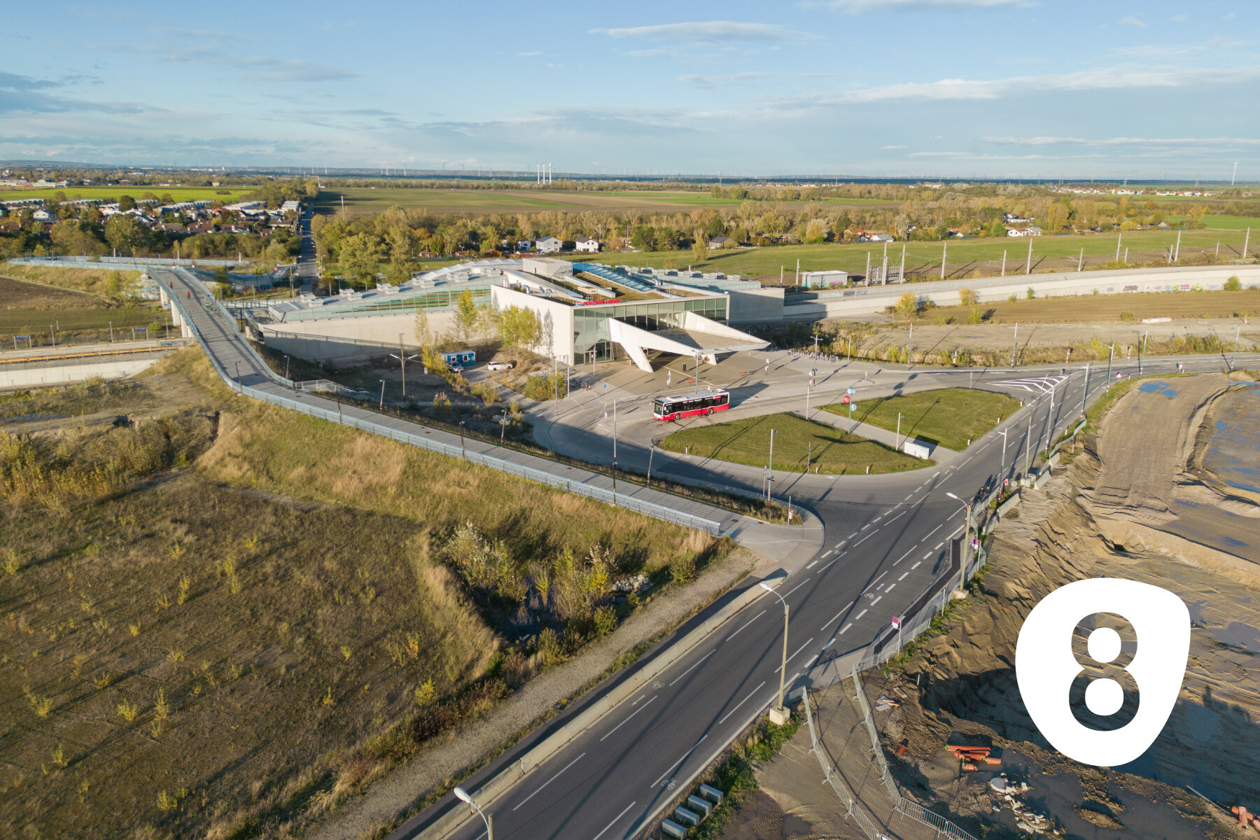 Ein moderner Bahnhof in Gelände mit Baufeldern und Siedlungen