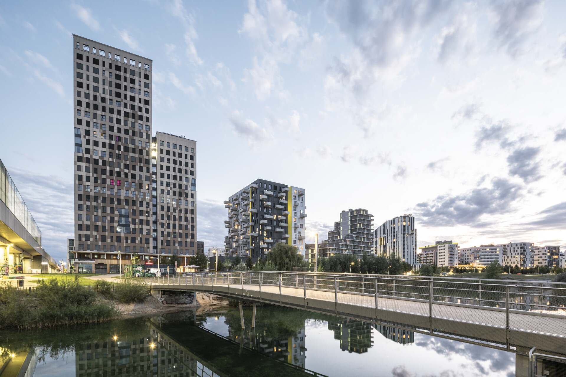 Skyline der Seestadt mit See im Vordergrund am Abend. 
