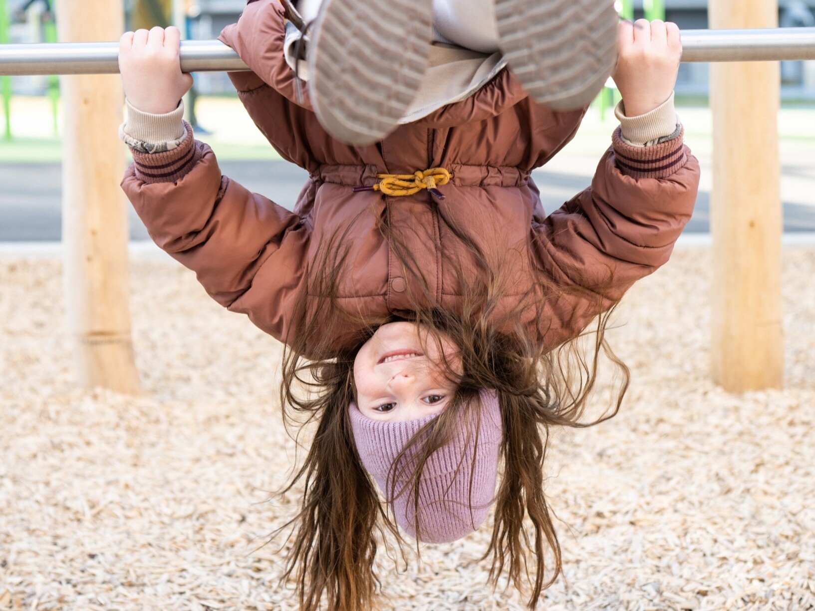 Ein Mädchen im Herbst klettert am Spielplatz