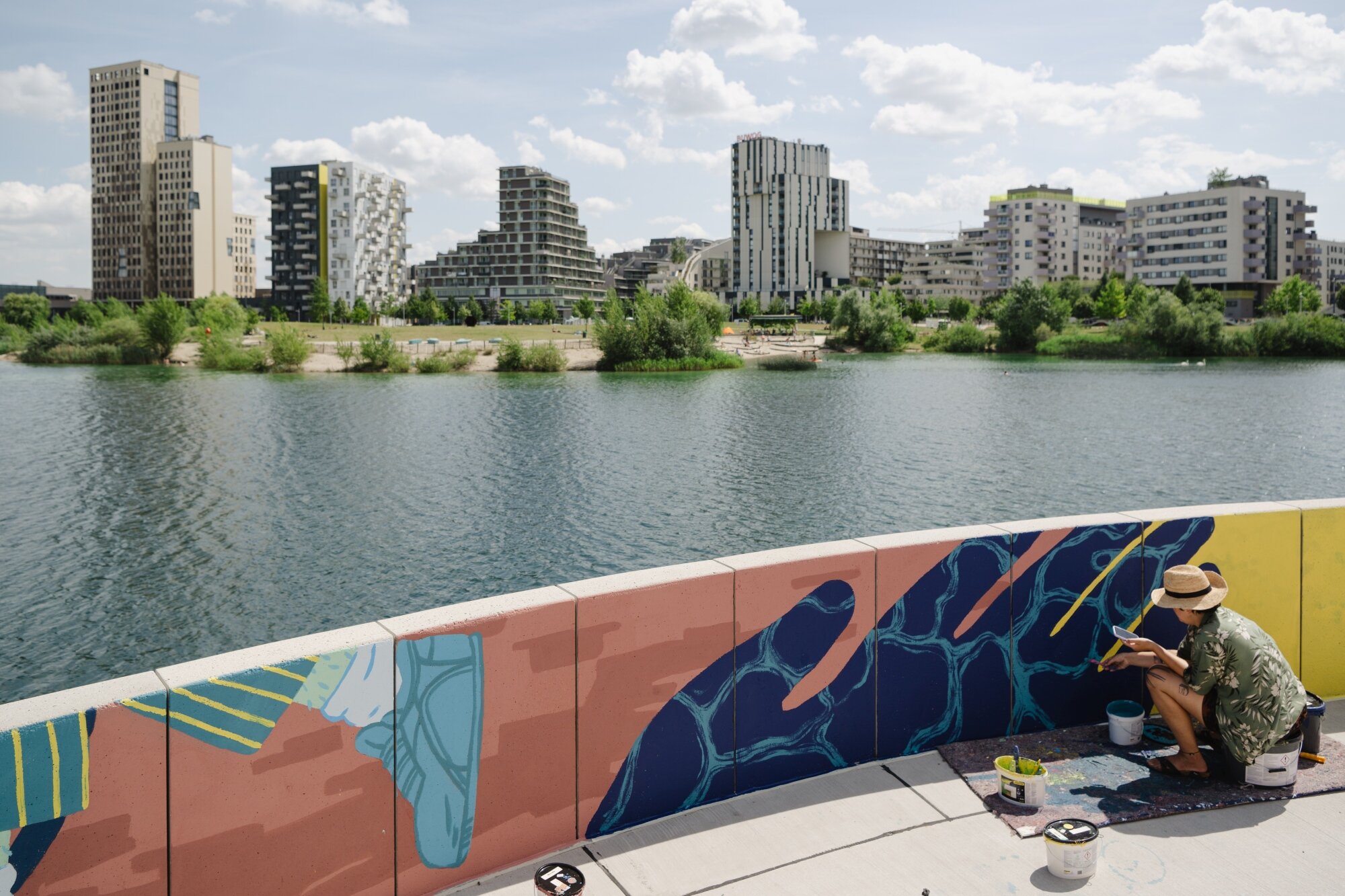 Das neue Mural am See entsteht Künstlerin malt ein großflächiges Mural an der Seestadtpromenade mit der Skyline im Hintergrund