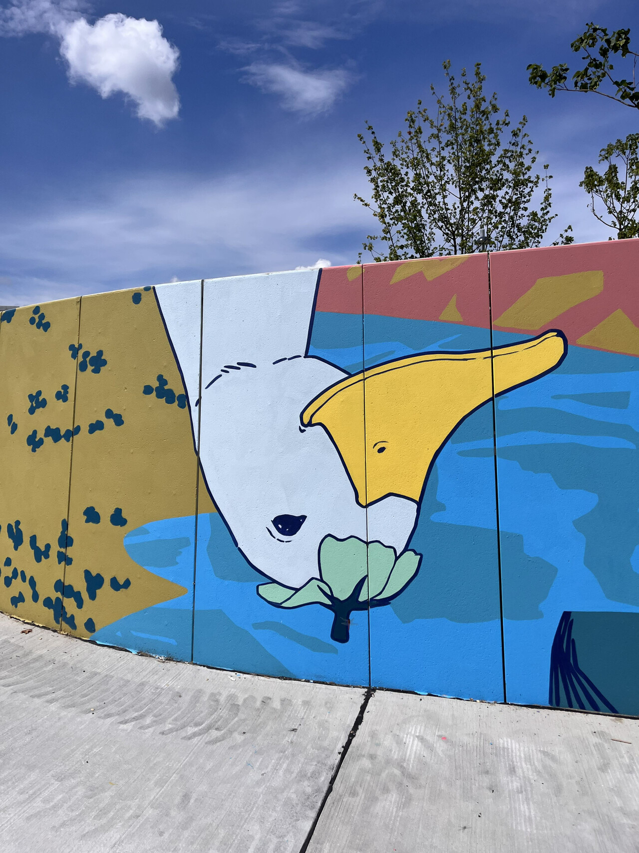Mural an der Wand einer Promenade: Entenkopf mit Blatt oben drauf am Kopf stehend