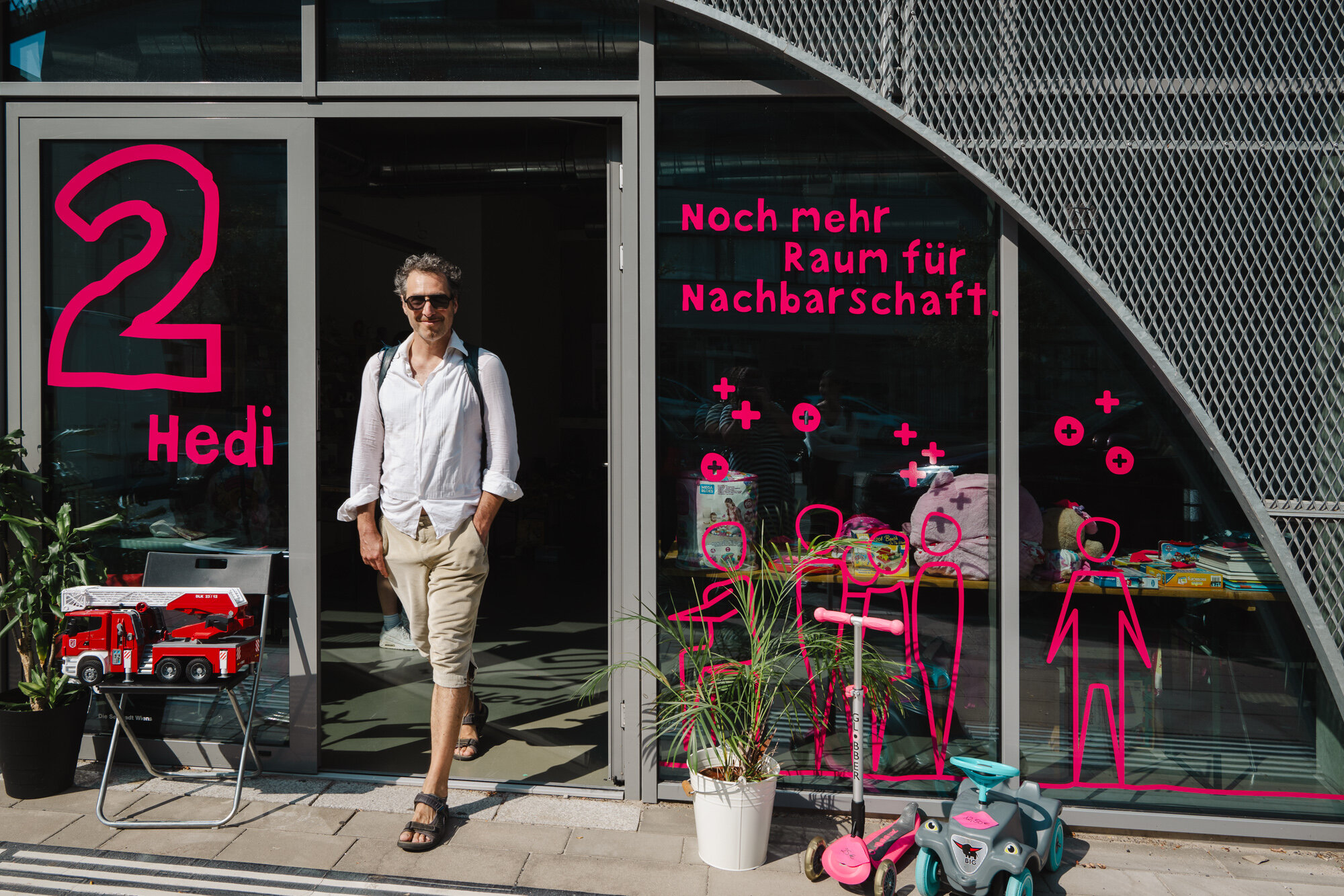 Nachbarschaftraum Hedi aspern Seestadt Mann kommt aus einem Nachbarschaftsraum mit dem Namen Hedi ,bunter Beklabung und Pflanzen