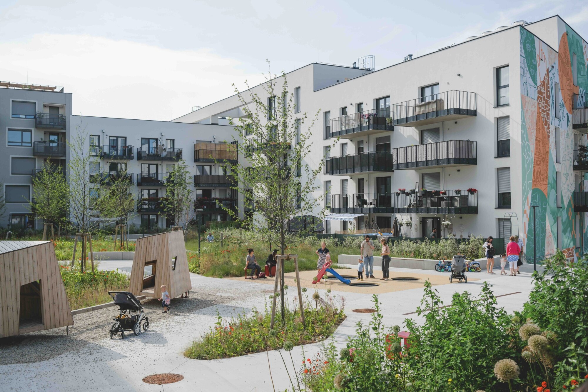 Nachbarschaftsfest im Gewerbehof begrünter Innenhof mit Spielplatz, Gebäuden mit vielen Balkonen und jungen Familien
