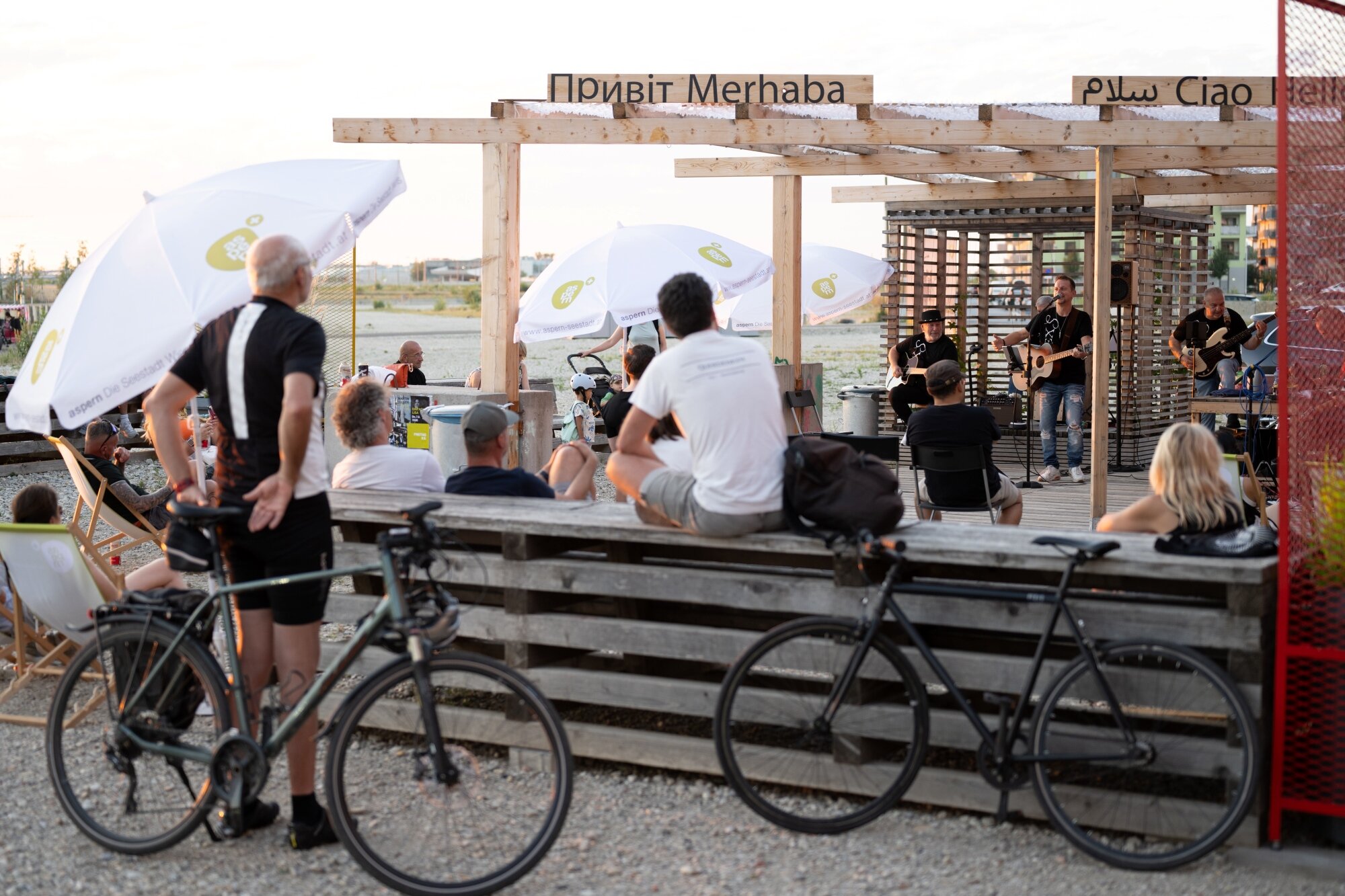 Nachbarschaftsterrasse am See mit Konzerten unterschiedliche Menschen bei einem kleinen Konzert auf einer Holz-Terrasse