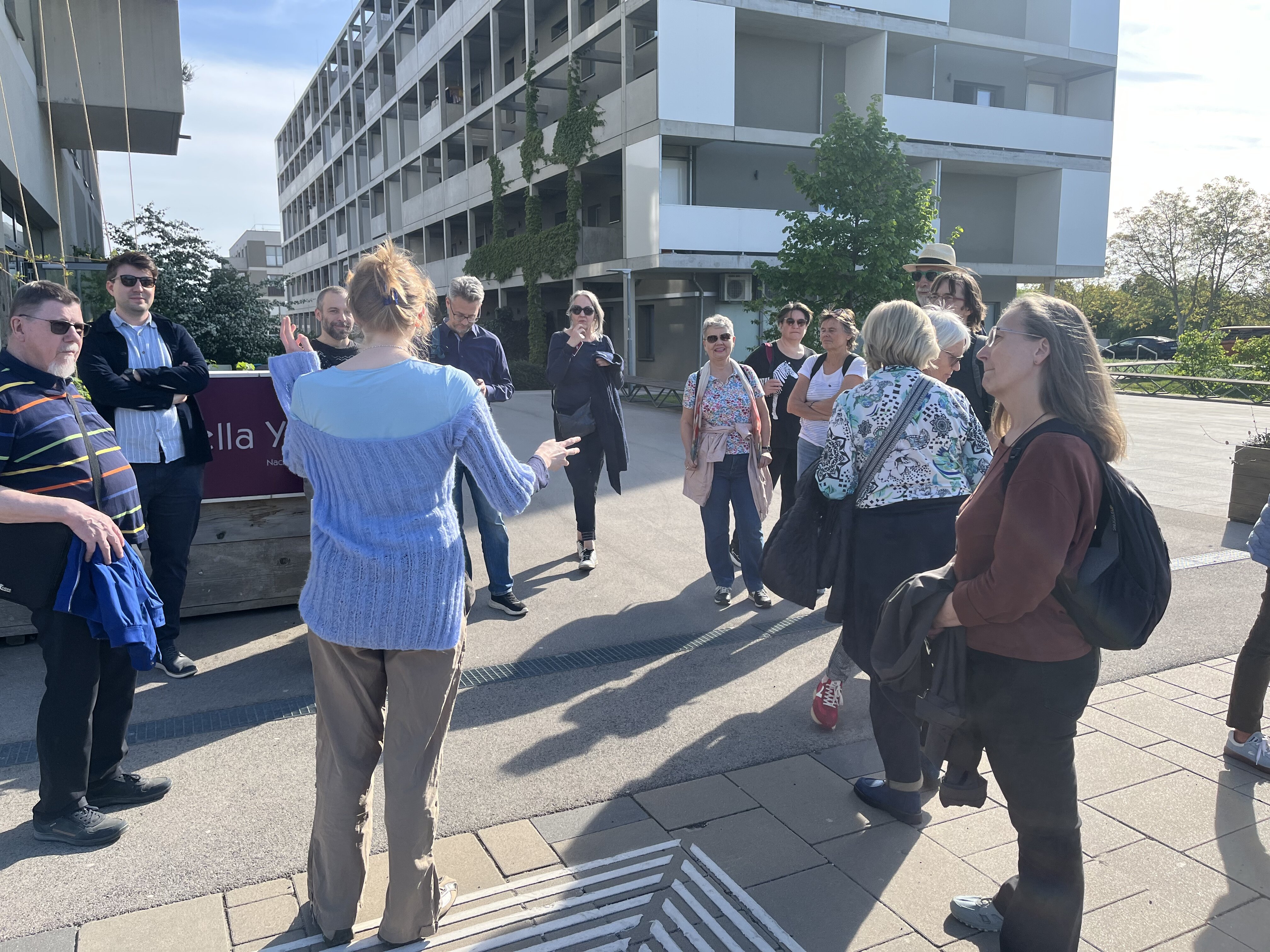 Stopp bei einer Grätzltour beim Yella Yella Nachbar_innentreff in der Seestadt, Menschen hören zu