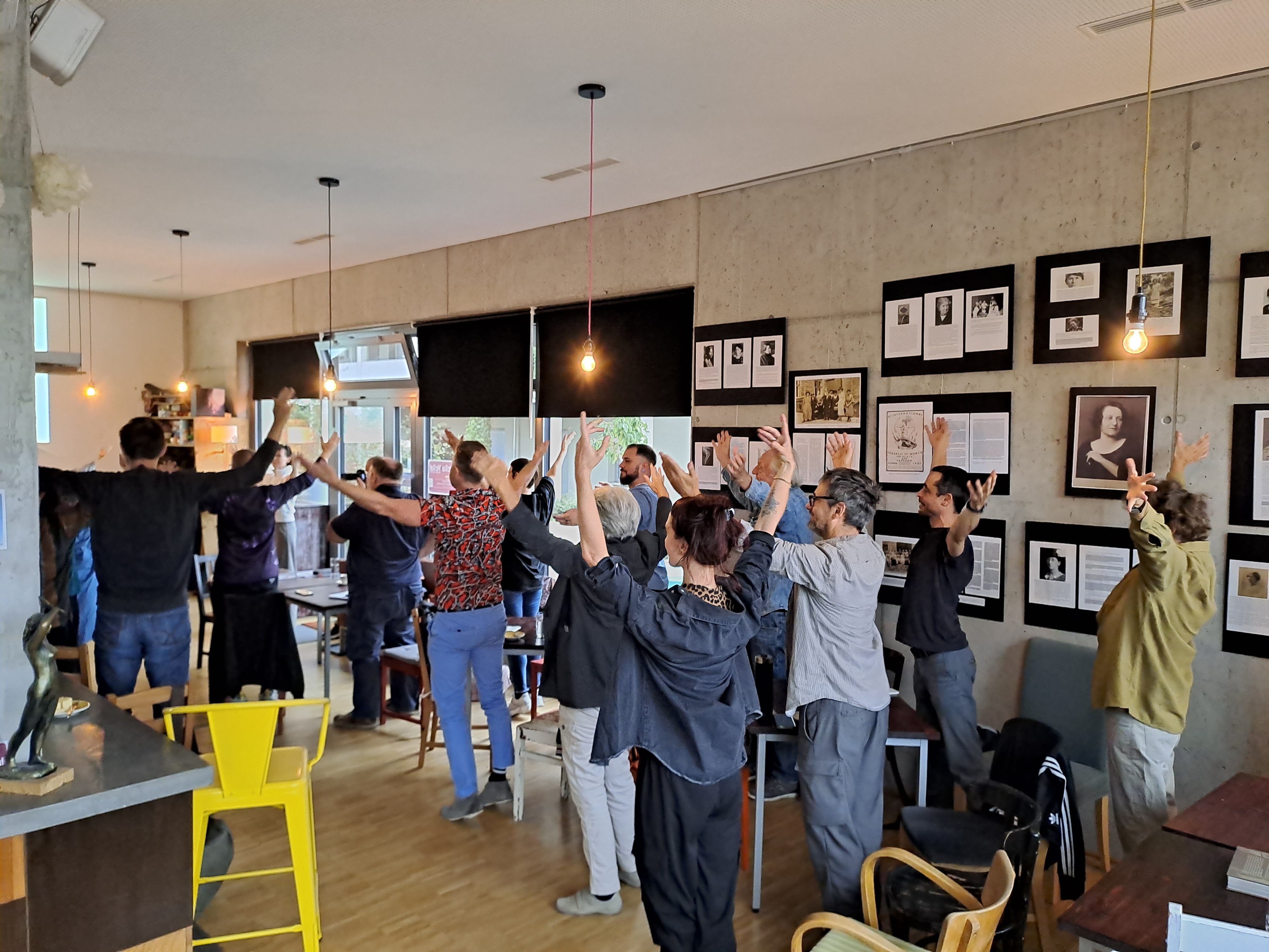 Gruppe von Menschen in Sitzreihen, haben alle die Hände gehoben