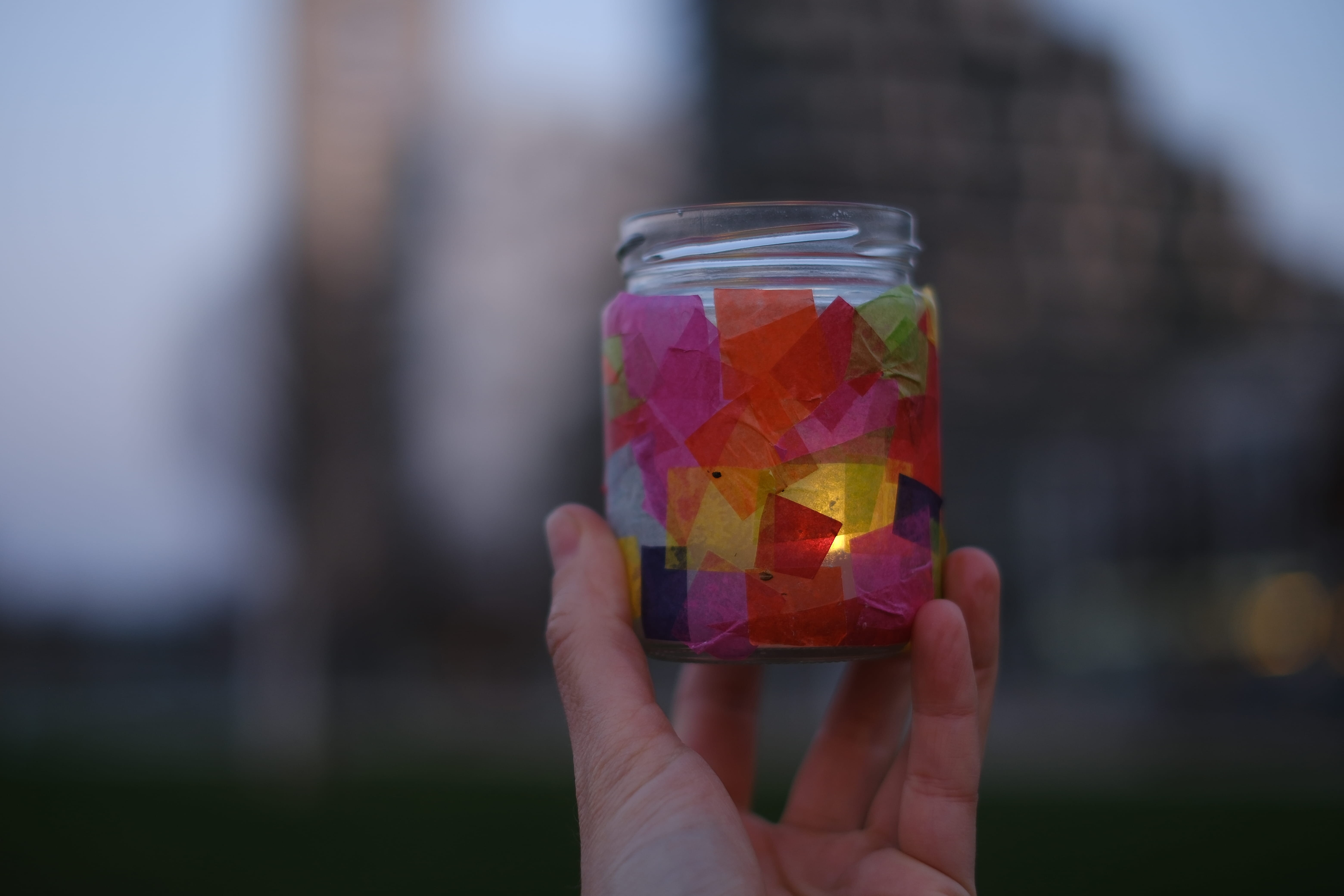 Bunt beklebtes Glas wird von einer Hand in die Kamera gehalten
