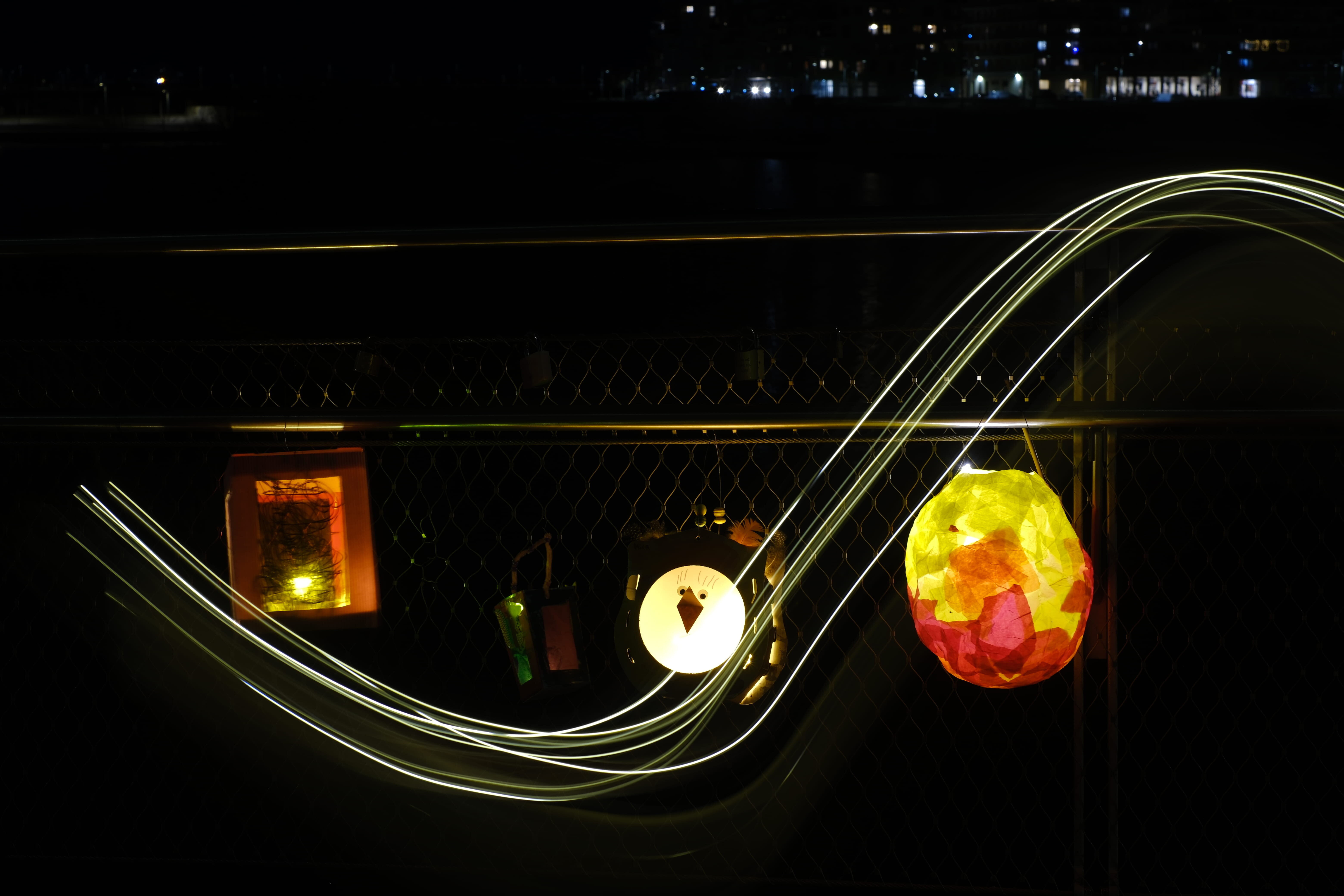 Laternen hängen an einem Geländer, es sind Lichtstreifen davor zu sehen