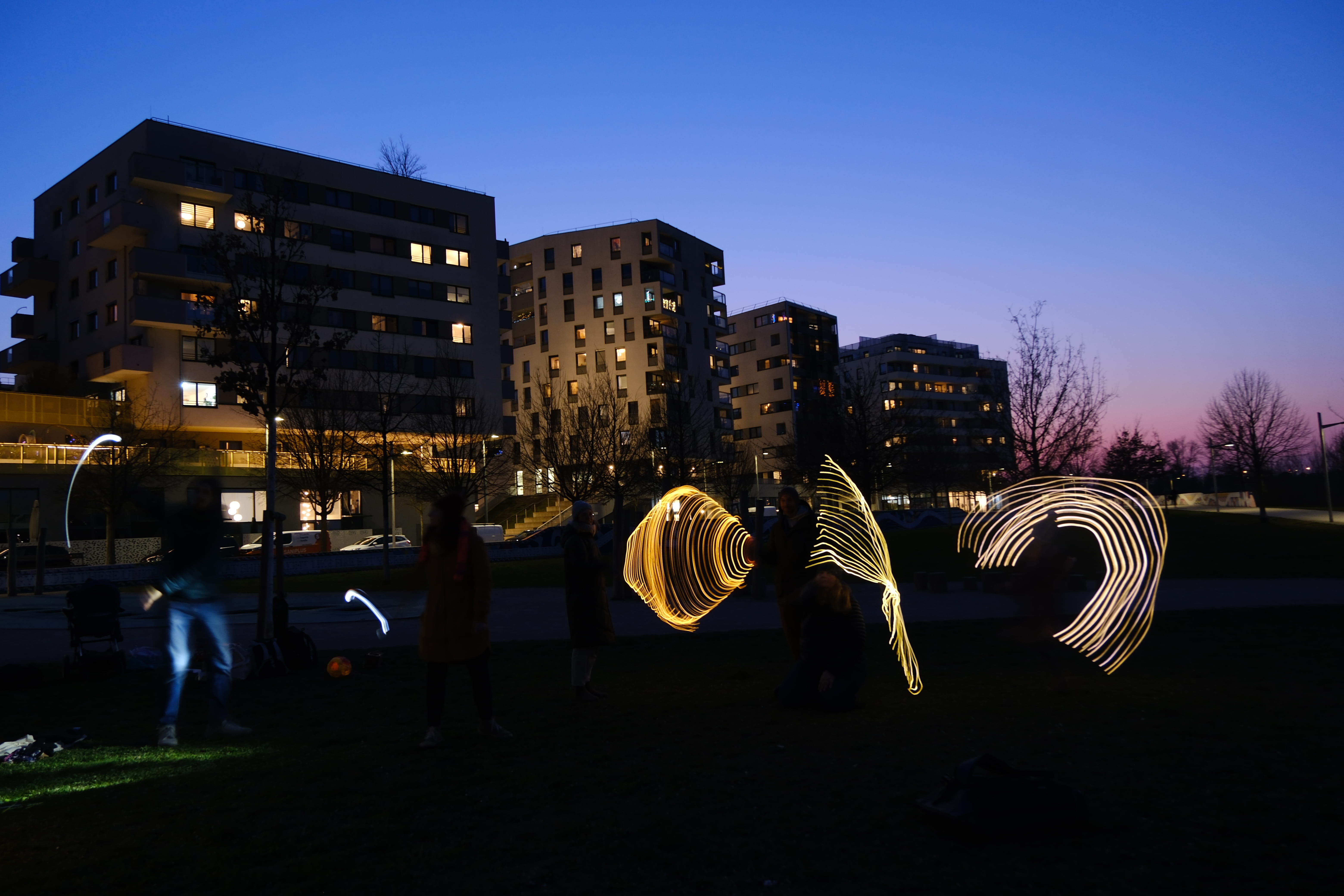 Lichterzeichnungen in der Luft, es ist dunkel und ein Park ist zu sehen
