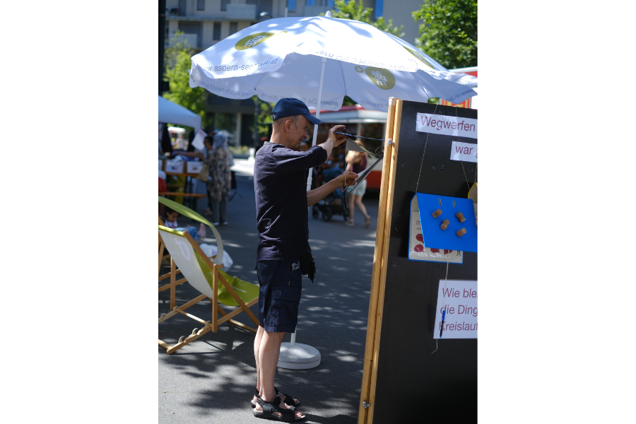 Person sieht sich einen Ordner, der an einer Ausstellungstafel aufgehängt ist an