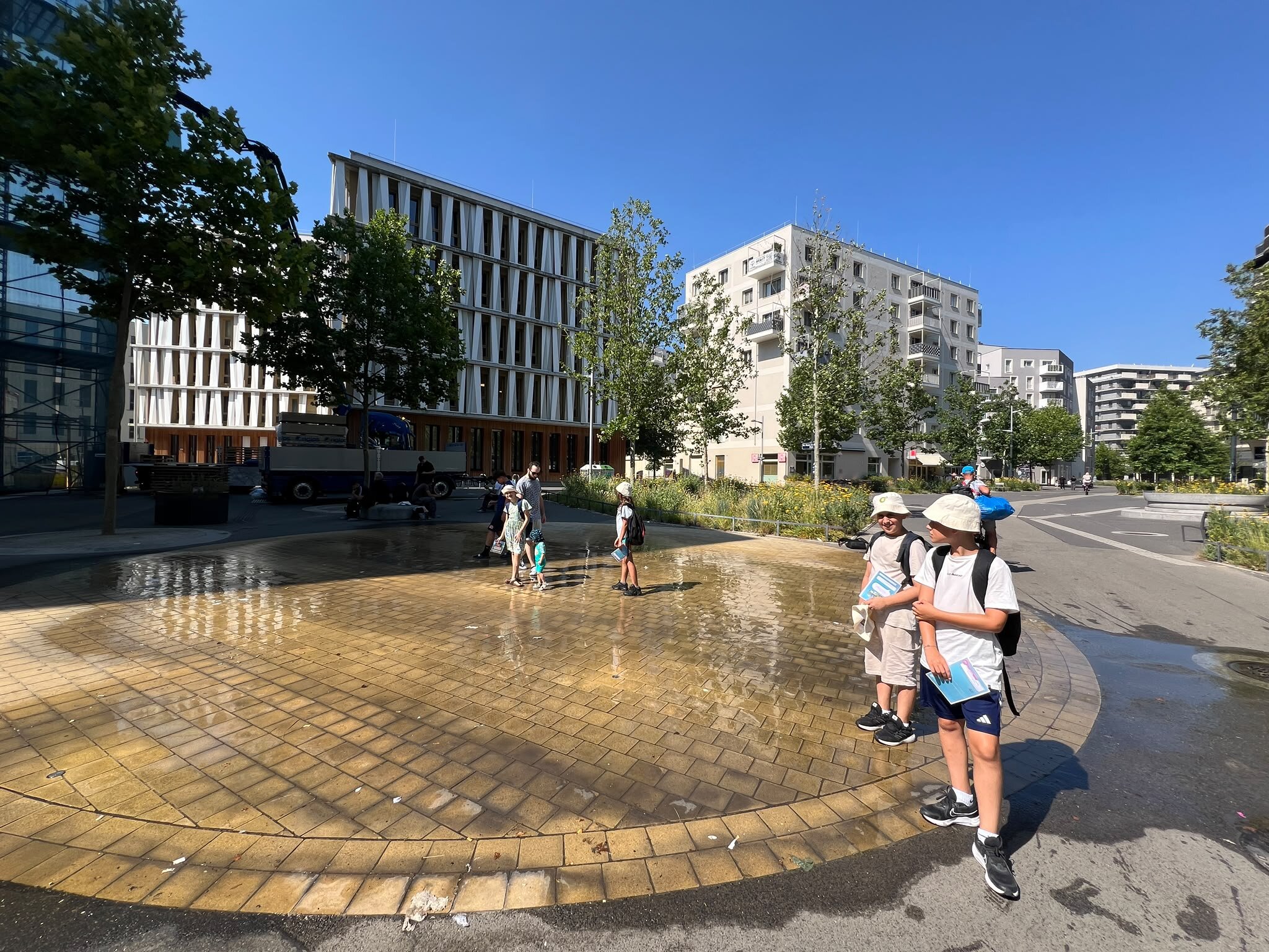 Jugendliche stehen bei einem Wasserspiel in der Seestadt