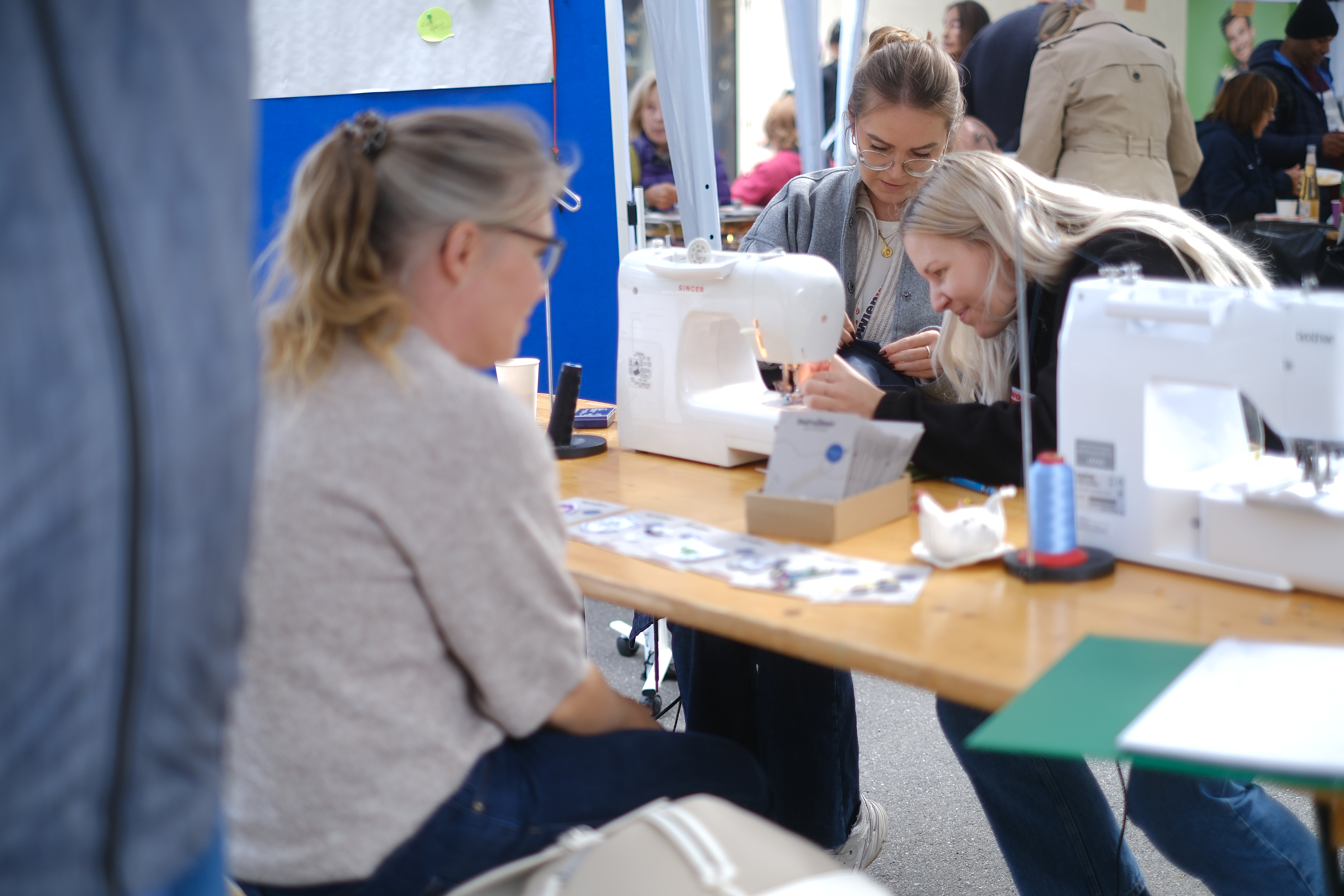 Frauen sitzen an einem Tisch und bedienen eine Nähmaschine
