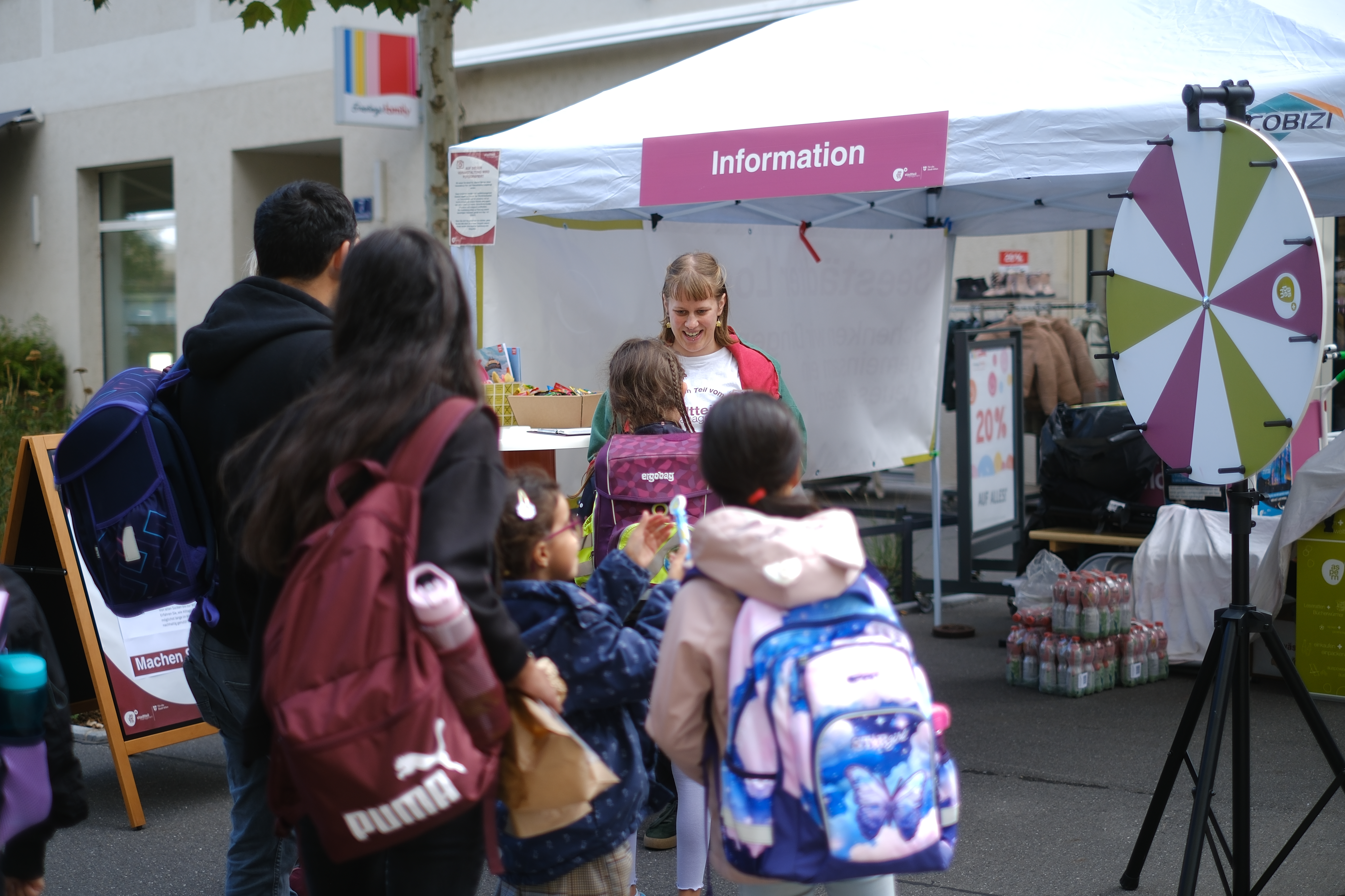 Personen stehen vor einem Infostand mit einem Glücksrad