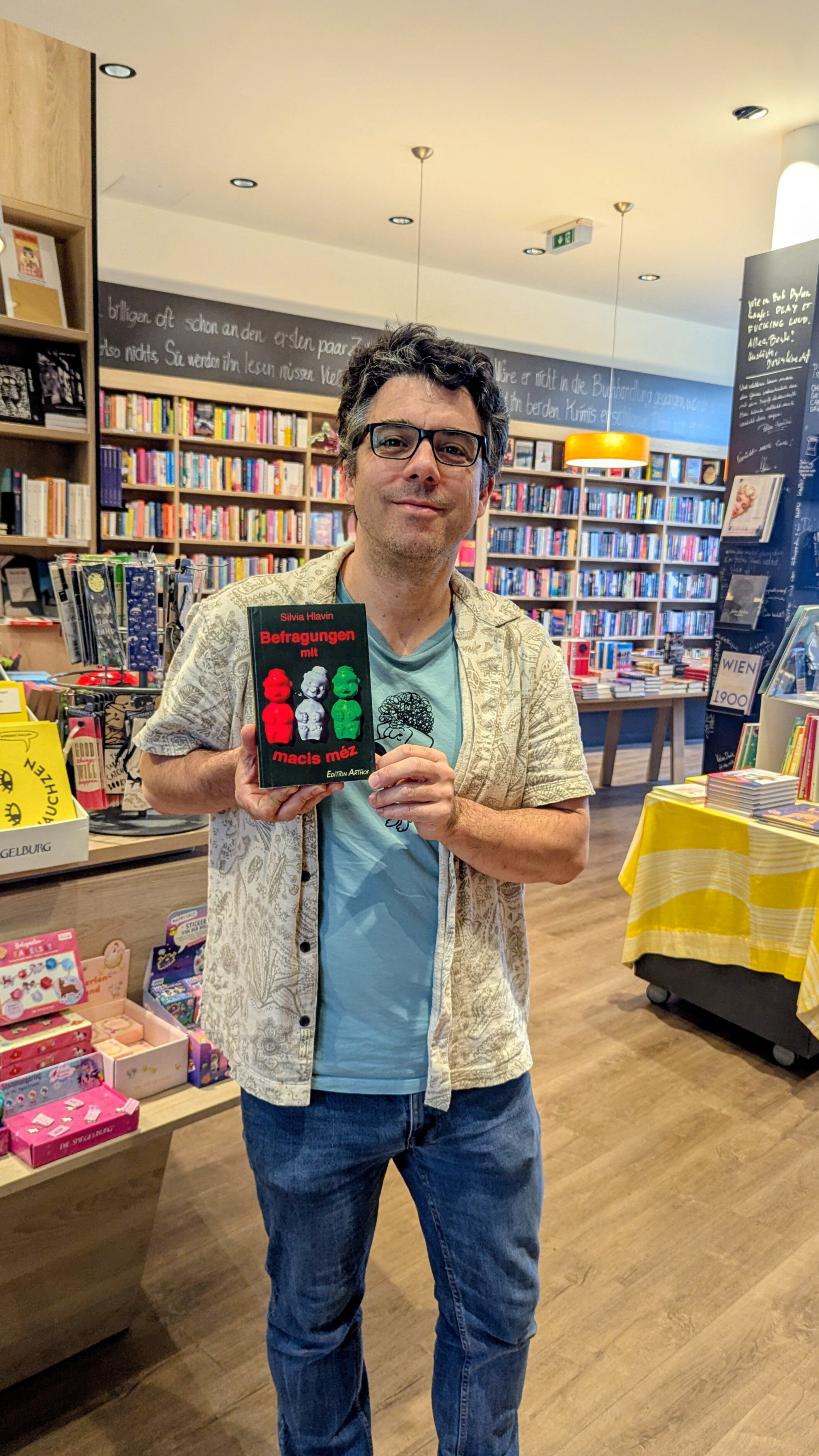 Ein Mann hält ein Buch in die Höhe und präsentiert es in die Kamera