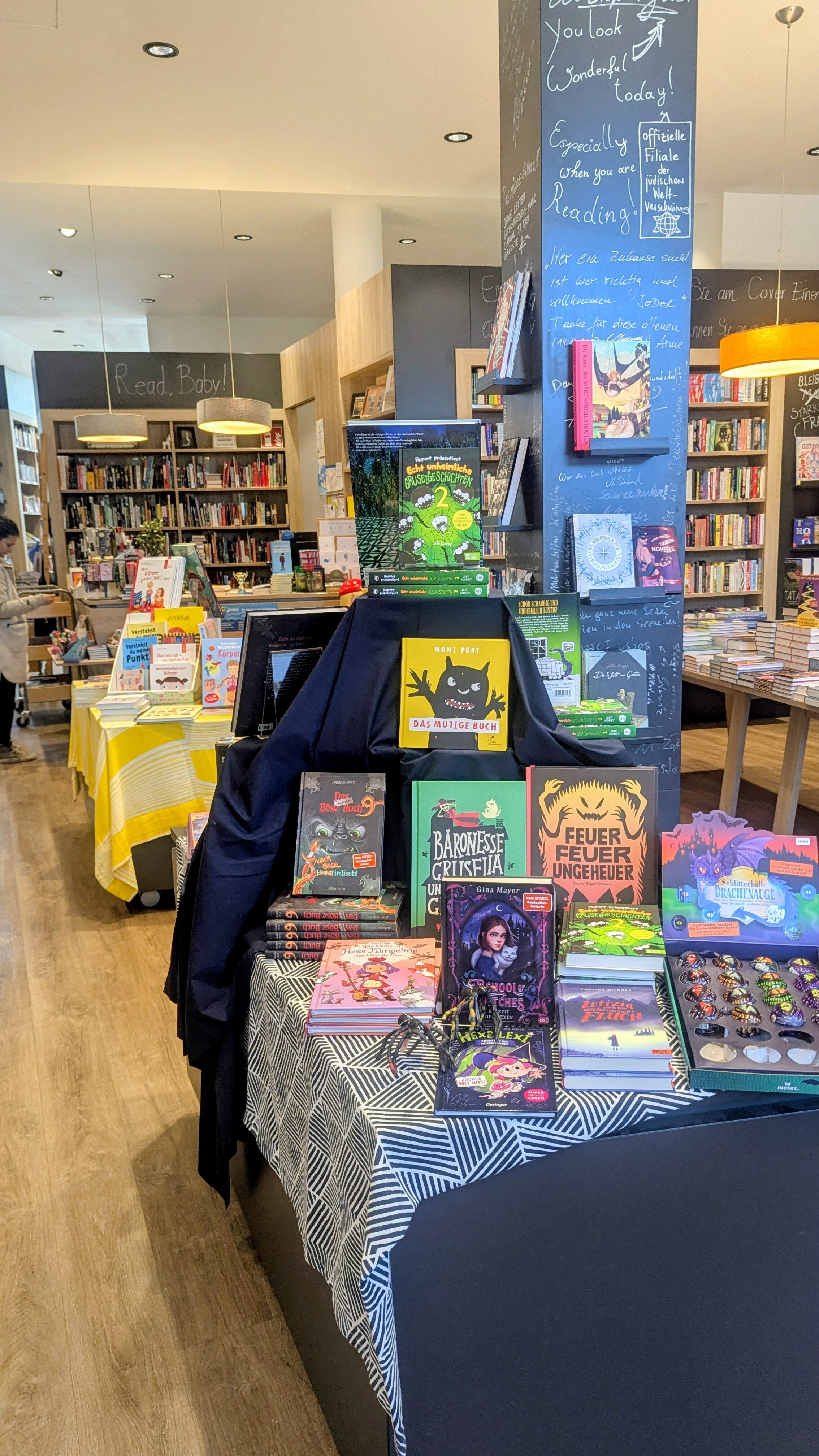 Ein Büchertisch in einer Buchhandlung mit Bücherregalen und weiteren Tischen im Hintergrund