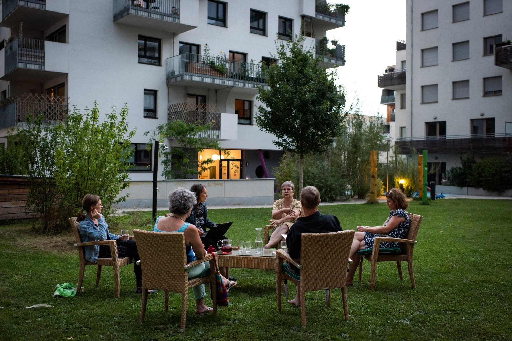 Frauen sitzen in einem großen grünen Innenhof mehrerer Baugruppen