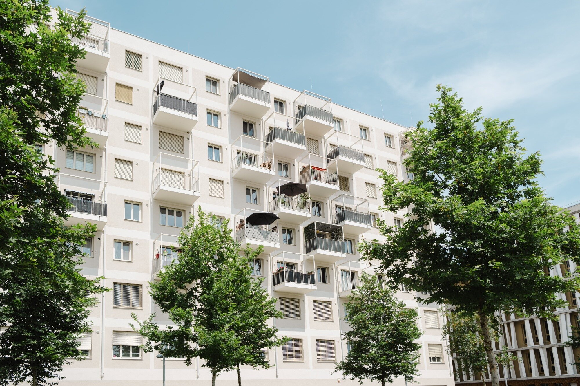 Wohnhaus mit vielen Balkonen einer Baugruppe mit Bäumen