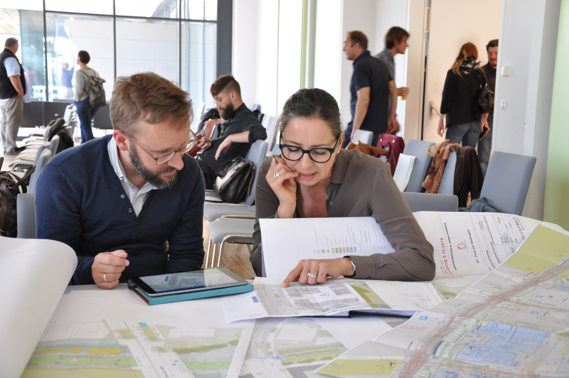 Zwei Personen schauen auf einen Plan und unterhalten sich. 