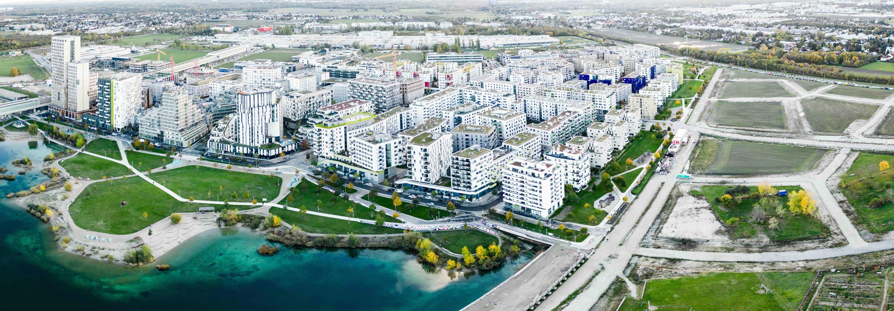 Drohnenaufnahme eines modernen Stadtgebiets mit See. 