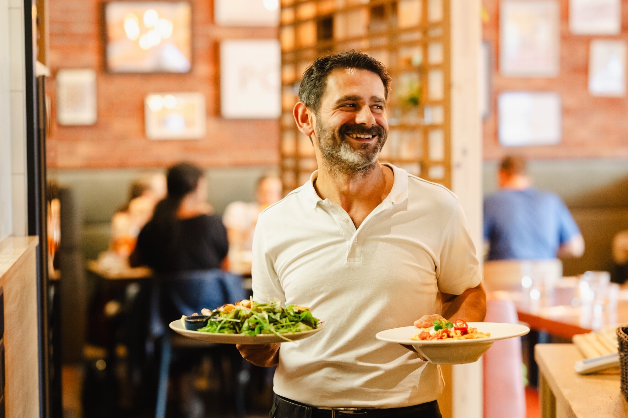 sympathischer Italiener serviert Pizza in einem schönen gemürlichen Lokal in der Seestadt