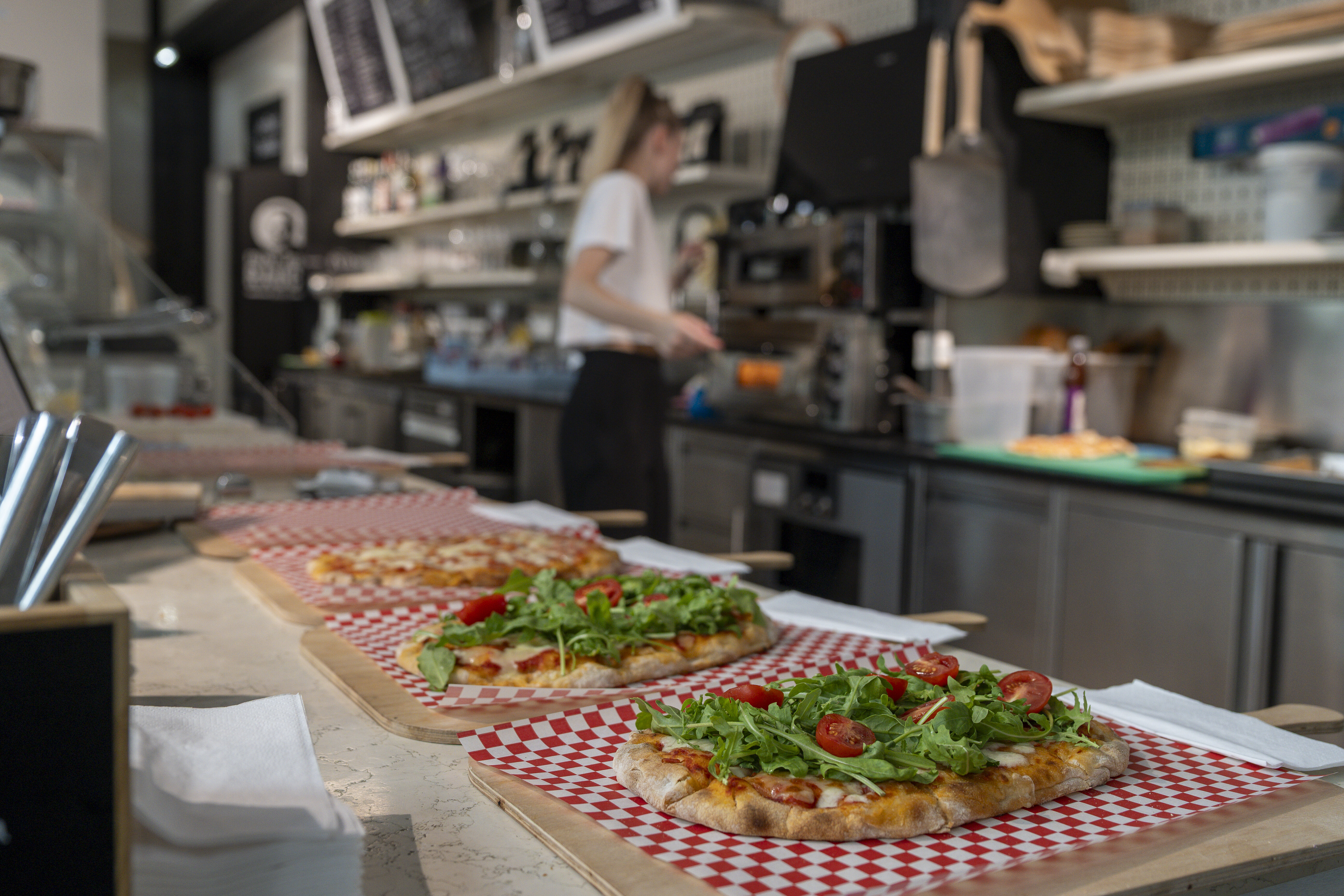 junge Frau bereitet Pinsas in einem modernen urbanen Lokal vor