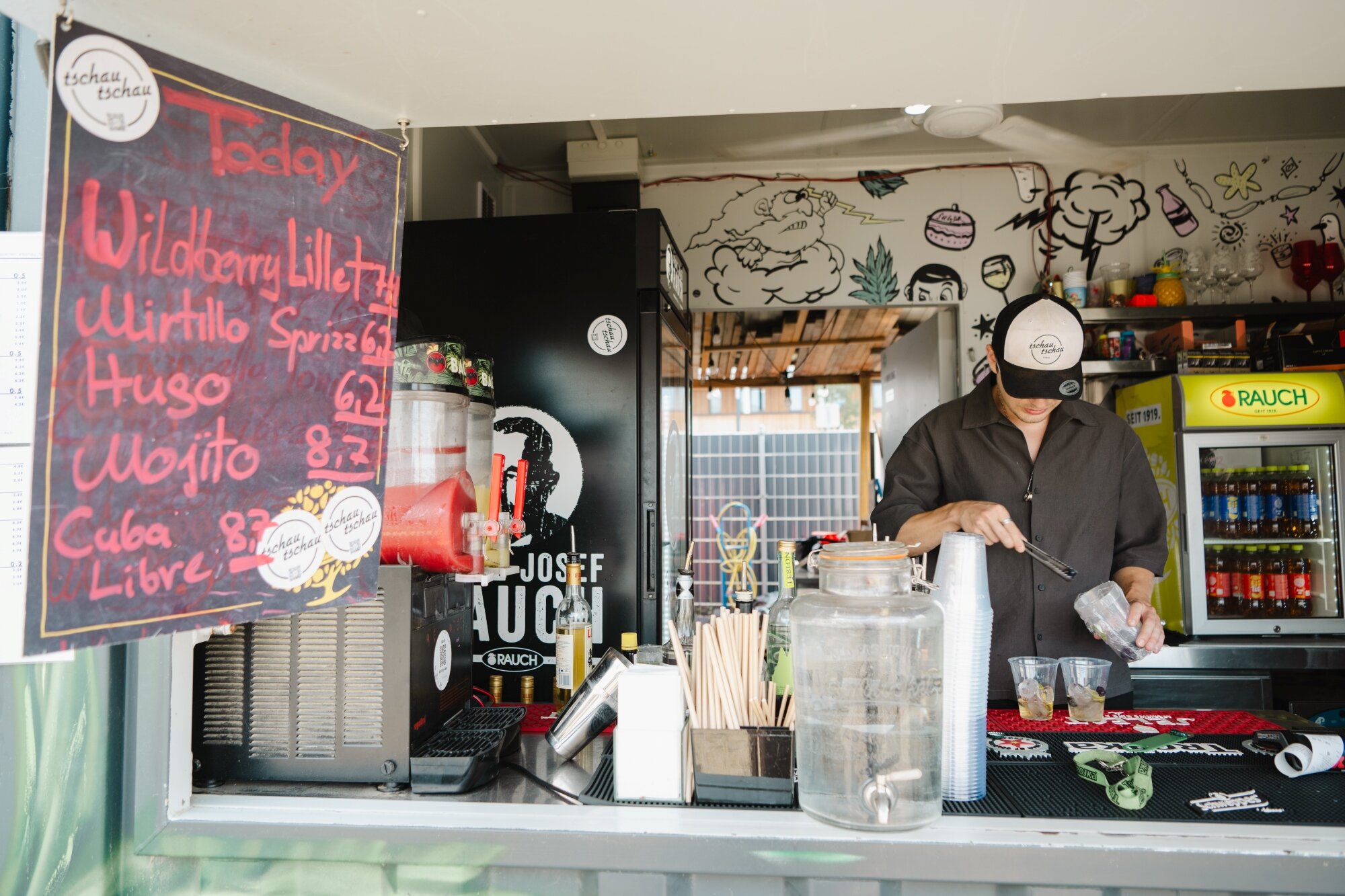 Pop-Up Bar Tschau Tschau im Seepark junger Kellner mixt Longdrinks in einer Pop-Up Bar am See