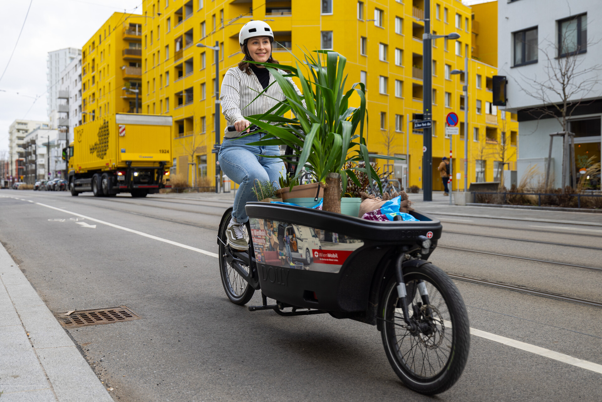 Frau auf einem Lastenrad von WienMobil Rad, die Pflanzen transportiert.