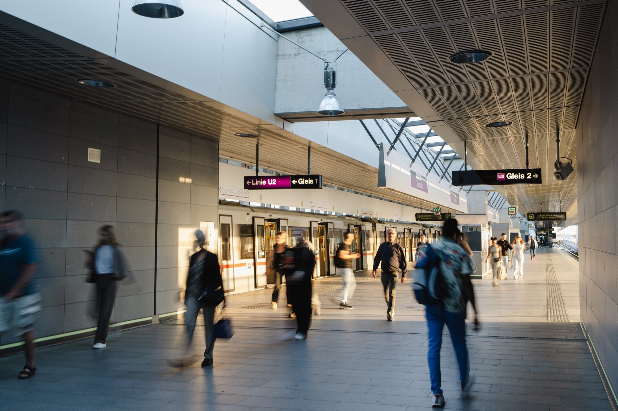 Menschen gehen durch eine moderne U-Bahn-Station mit viel natürlichem Licht