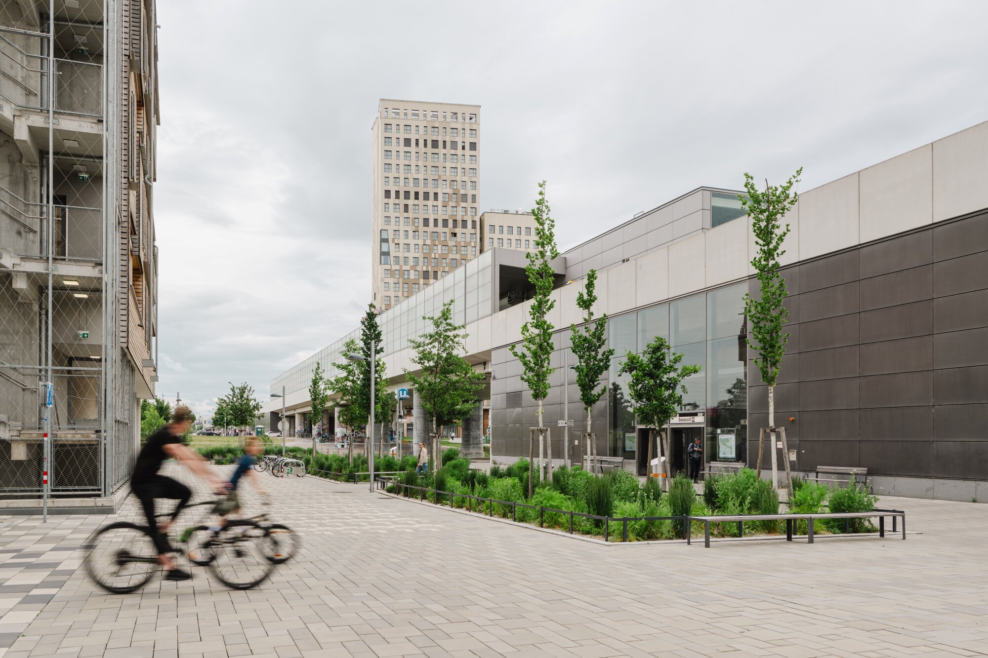 mit Rad und U-Bahn gut unterwegs in der Seestadt Radfahrer auf breiten Radwegen mit Begrünung im Quartier am Seebogen und vor der U-Bahn-Station