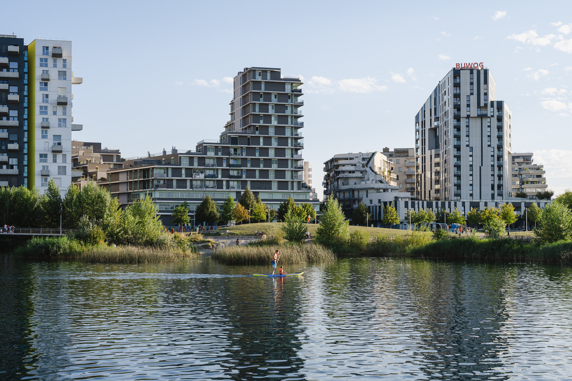 Eine Person fährt mit einem SUP am See mit Hochhäusern im Hintergrund