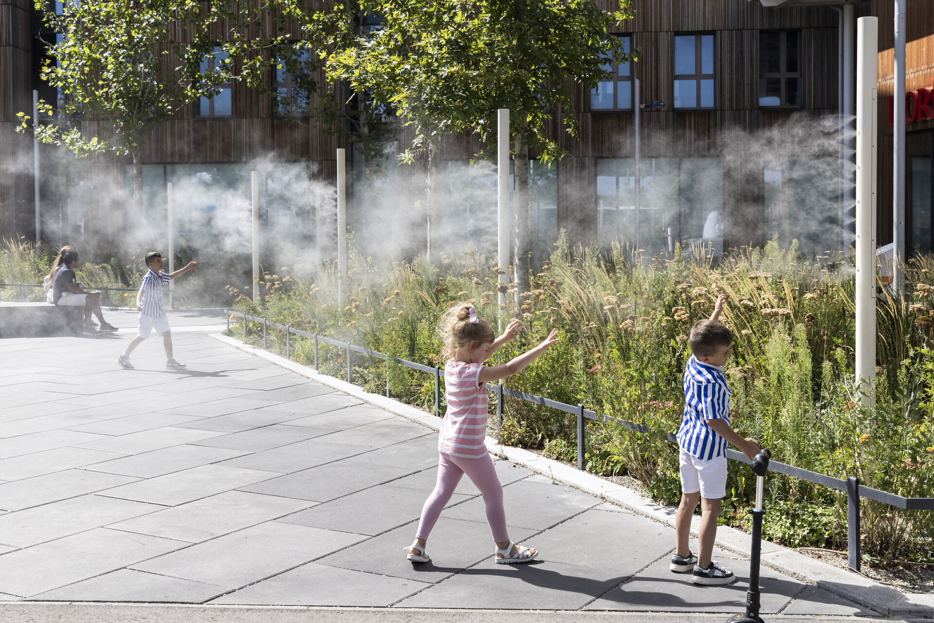 Kinder spielen unter Nebelduschen.