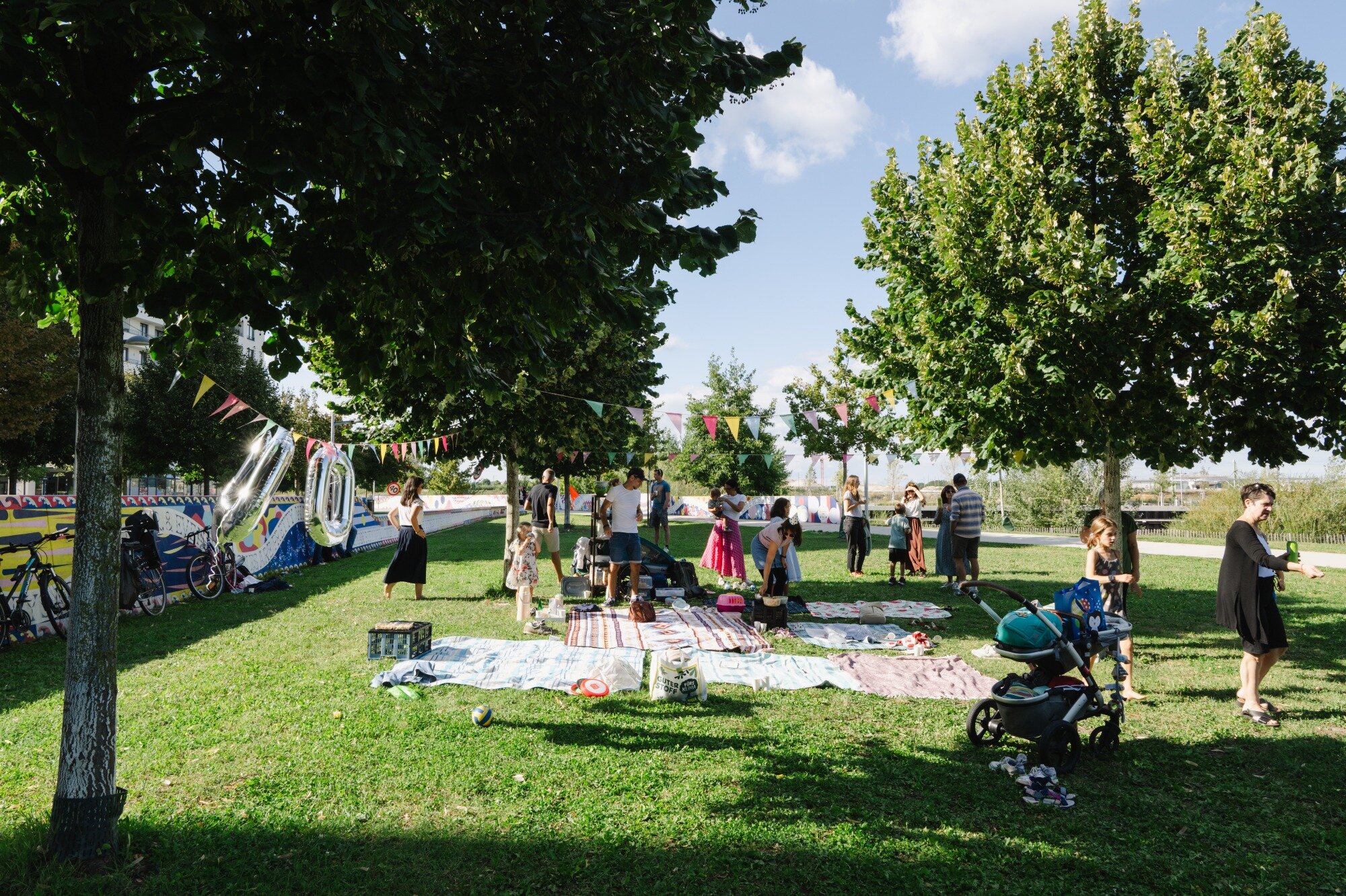 Geburtstag feiern im Seepark Gruppe mit Erwachsenen und Kindert feiert im Seepark ein Geburtstagsfest auf der Wiese mit Bäumen