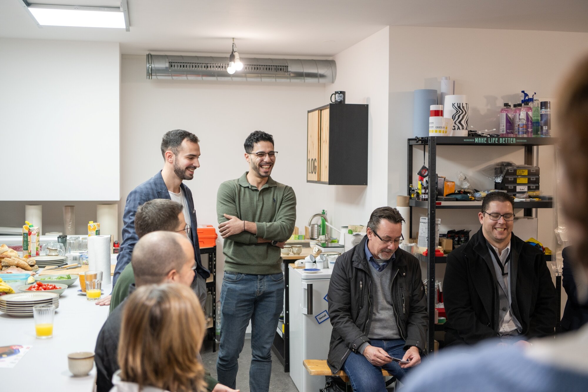 entspannter Austausch zwischen Unternehmer*innen in der Seestadt eine Gruppe Unternehmer und Unternehmerinnen in einer Werkstatt mit gedeckten Tisch tauschen sich in entspannter Atmosphäre üner ihre Ideen aus