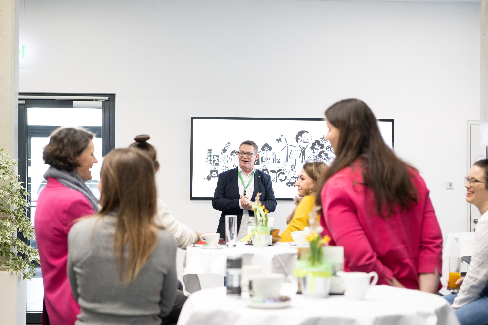 Unternehmer und Unternehmerinnen unterhalten sich in einem modernen Businessraum mit gedeckten Stehtischen