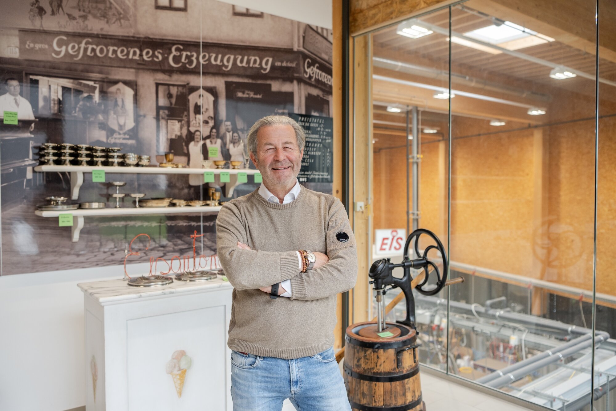 leger gekleideter Mann steht vor alten Utensilien einer modernen Anlage zur Eisproduktion 