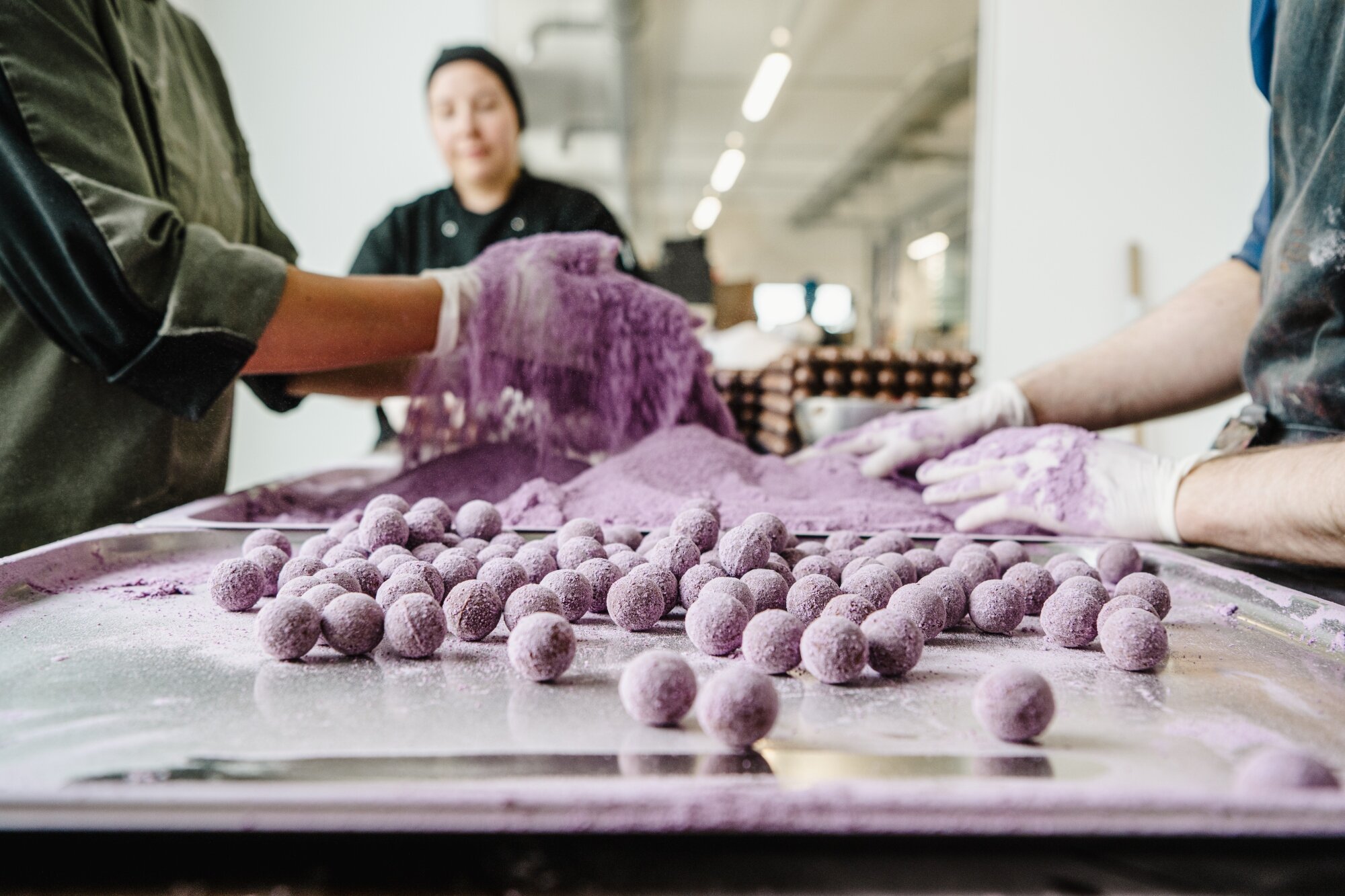 mehrere Menschen prodizieren Konfekt von Xocolat in einer modernen Halle im Gewerehof in der Seestadt