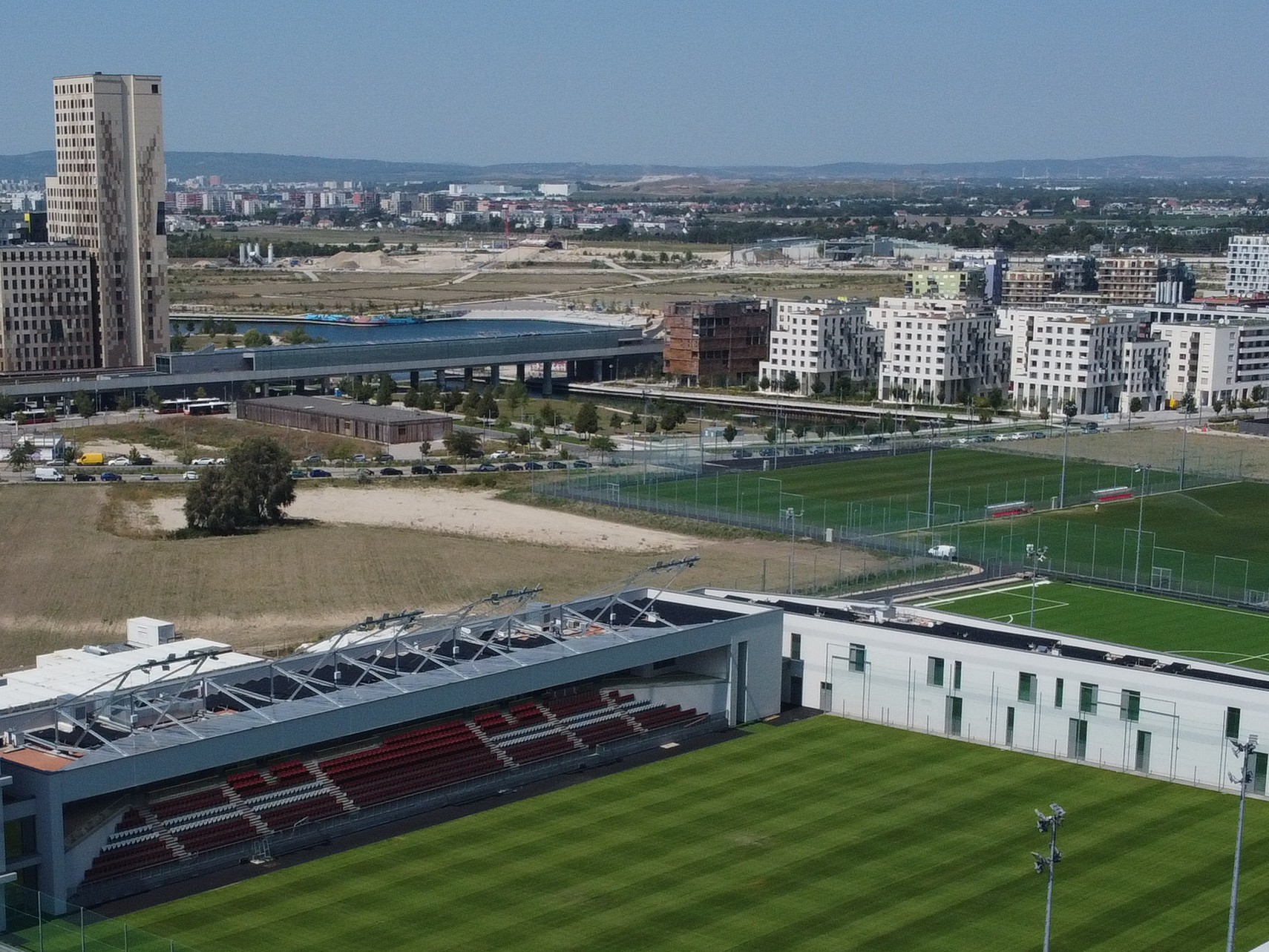 grüner Fußballplatz mit Tribüne und die Skyline von aspern Seestadt